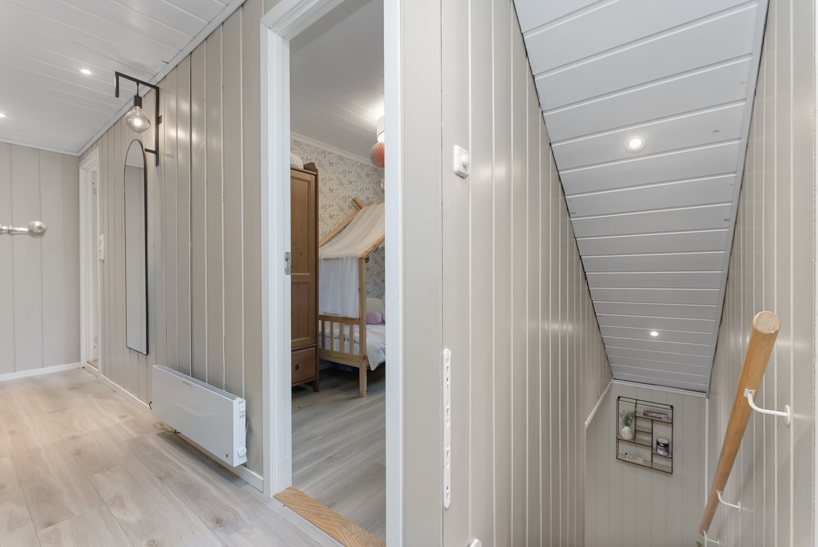 Entréen har lyse panelvegger og moderne belysning, med enkel tilgang til både soverom og trapp ned. Galleribilde