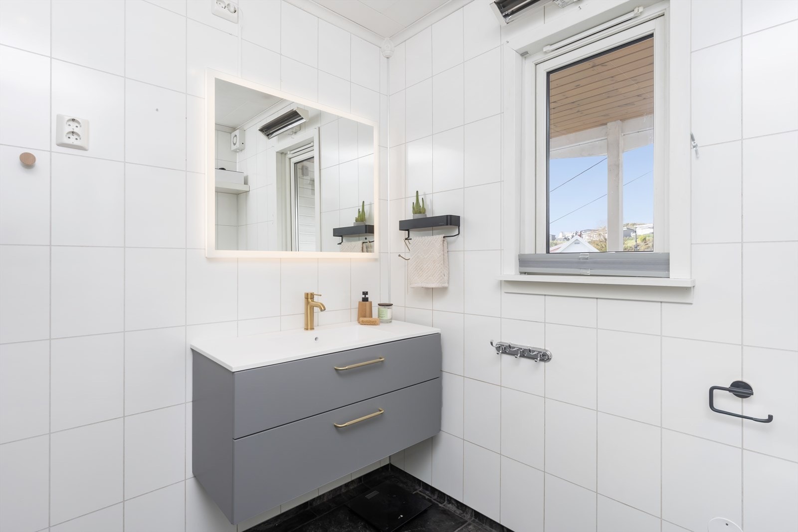 Badet har en moderne servant med skuffer og et stort speil med innebygd belysning. Galleribilde