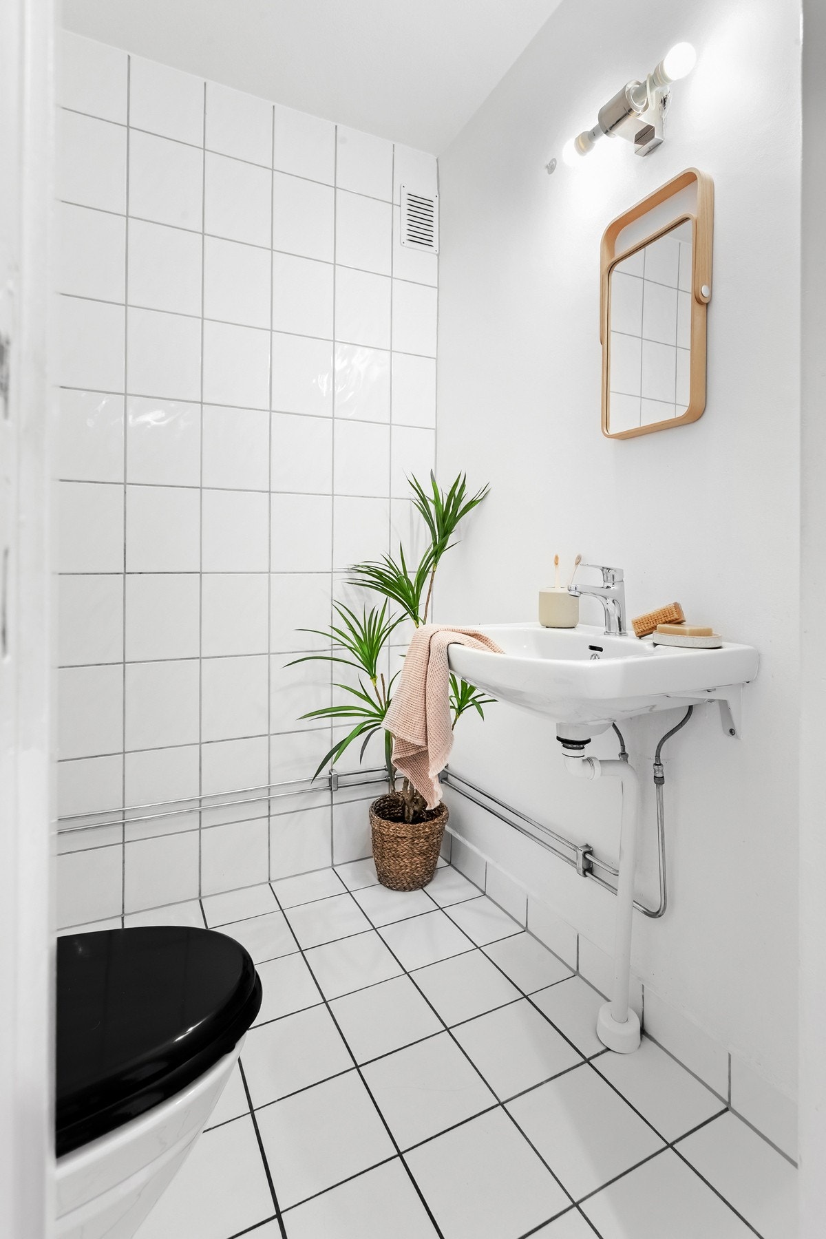 Flislagt gulv med termostatstyrte varmekabler. Servant på vegg, med ny kran fra 2025, med lysarmatur montert over servanten. Galleribilde