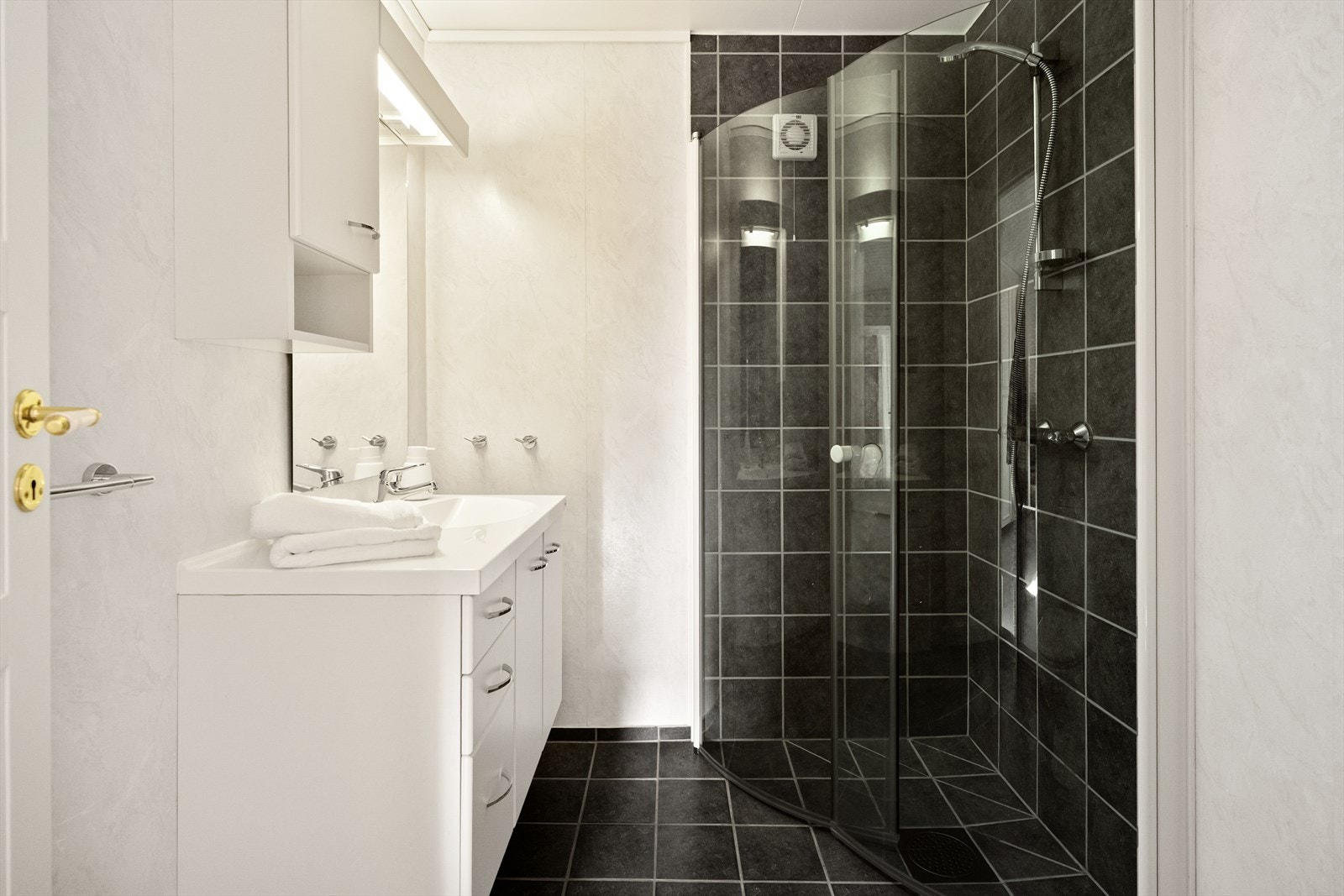 - Baderommet har flislagt dusjhjørne og gulv, WC og stort baderomsmøblement med speil og belysning - Galleribilde