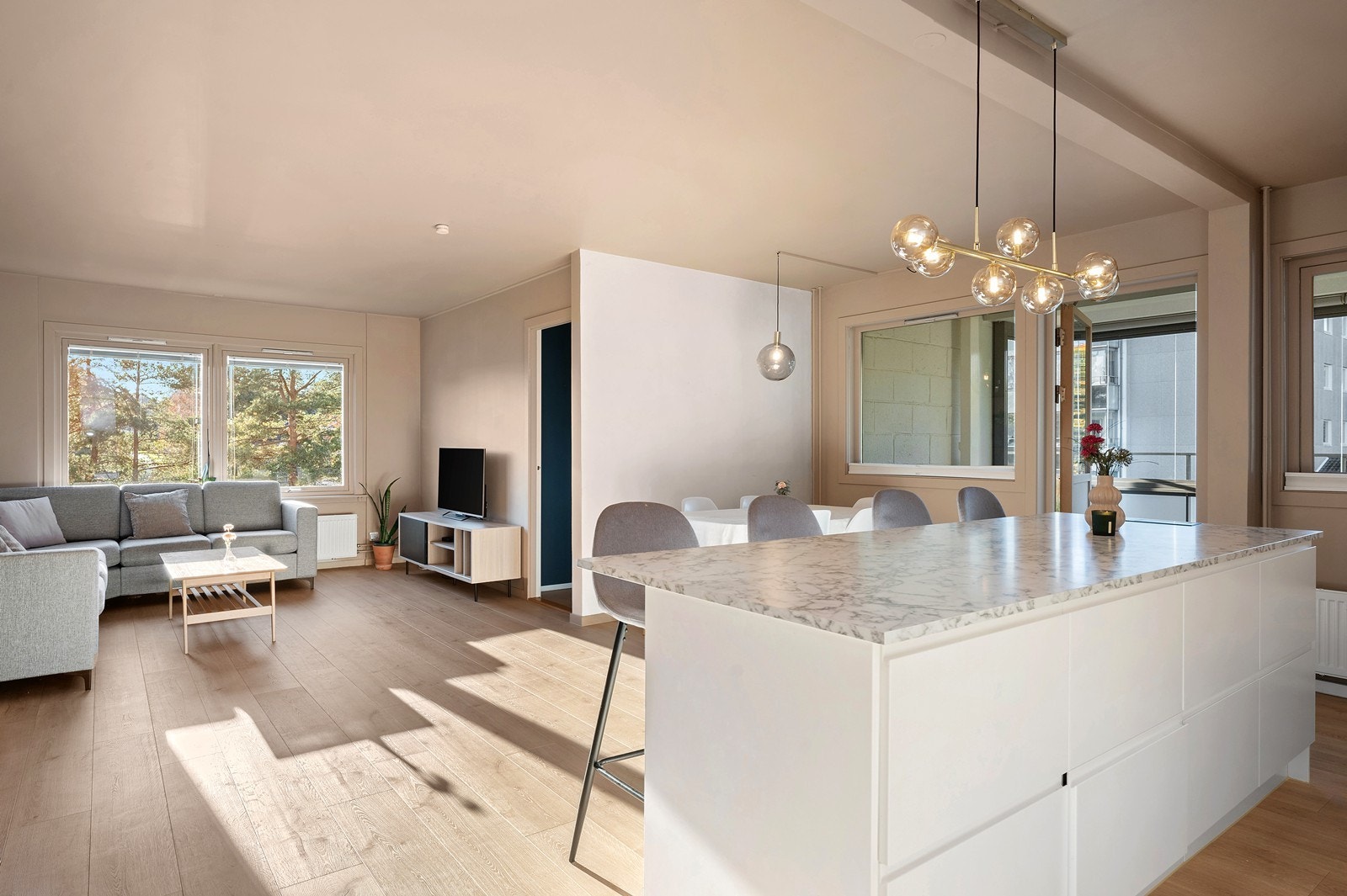 Romslig stue/kjøkken, som er pent oppusset med tidsriktige materialer. Det er slette, rene flater i himling og på vegger, og på gulvet er det moderne en-stavs laminat Galleribilde