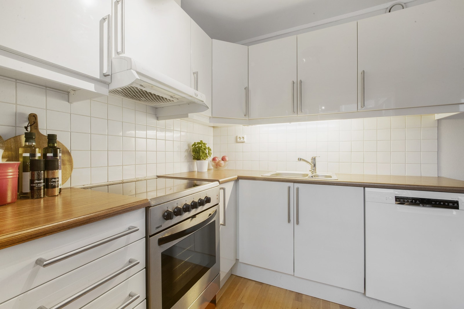 Mellom benkeplate og overskap er det flislagte vegger, overskapsbelysning og praktiske stikkontakter Galleribilde