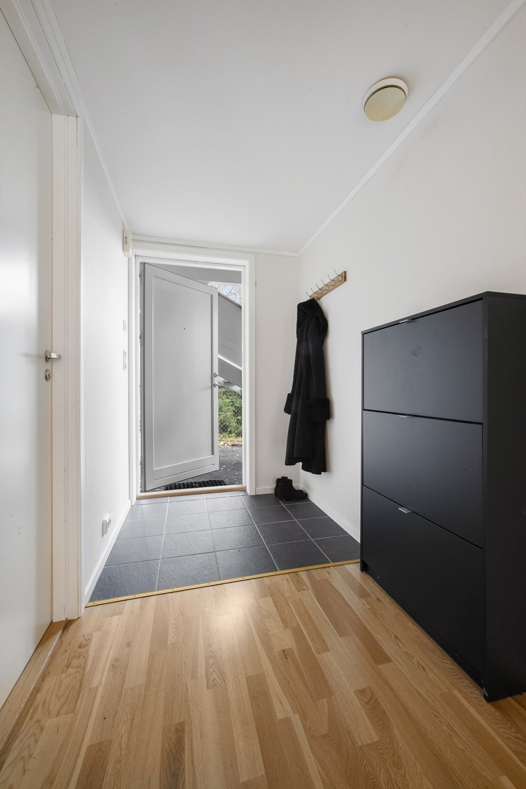 Man kommer inn i en flislagt entré med gulvvarme og knaggrekker for å henge av seg ytterklær Galleribilde