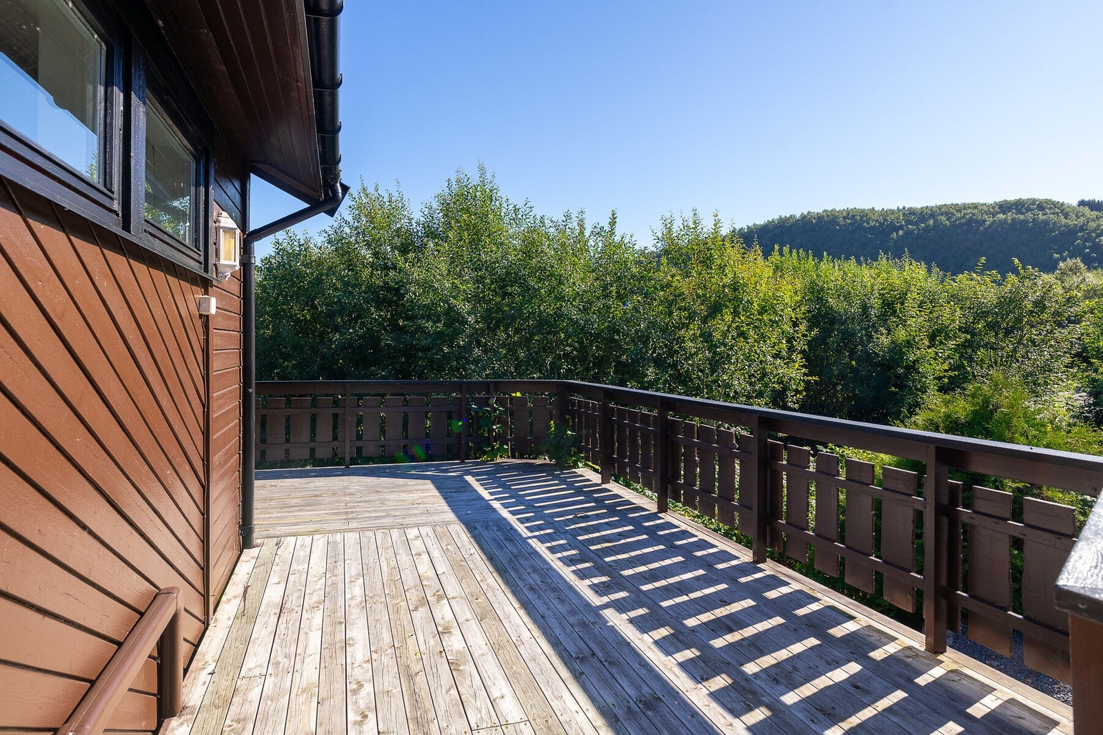 Romslig veranda som strekker seg rundt to sider av boligen og gir gode solforhold store deler av dagen. Galleribilde