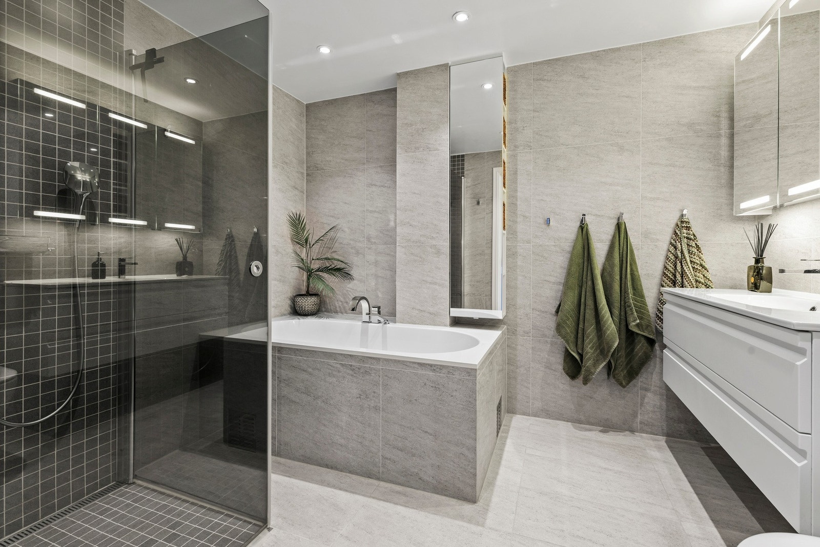 Rommet er utstyrt med servant, veggmontert toalett, samt innmurt badekar og dusjhjørne med svingbare glassdører Galleribilde