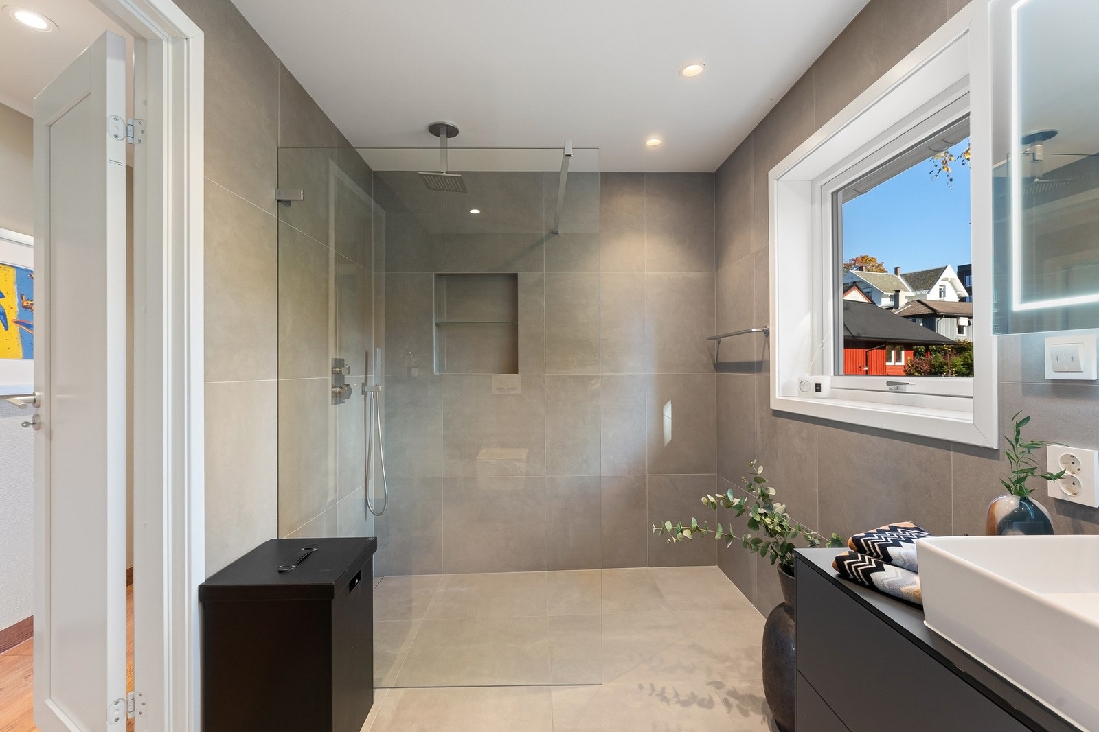 Badet fremstår moderne, med regnfalldusj og fliser i et elegant uttrykk. Galleribilde