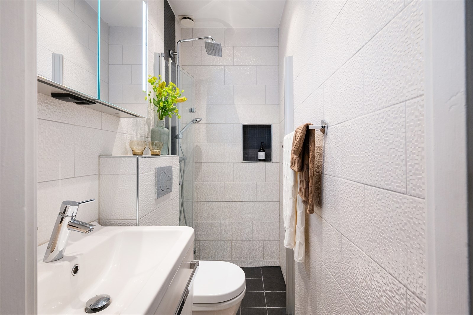 Pent og tidløst baderom med malt himling og innfelte downlights. Vegger og gulv er belagt med fliser, og gulvet har elektrisk gulvvarme for ekstra komfort. Galleribilde