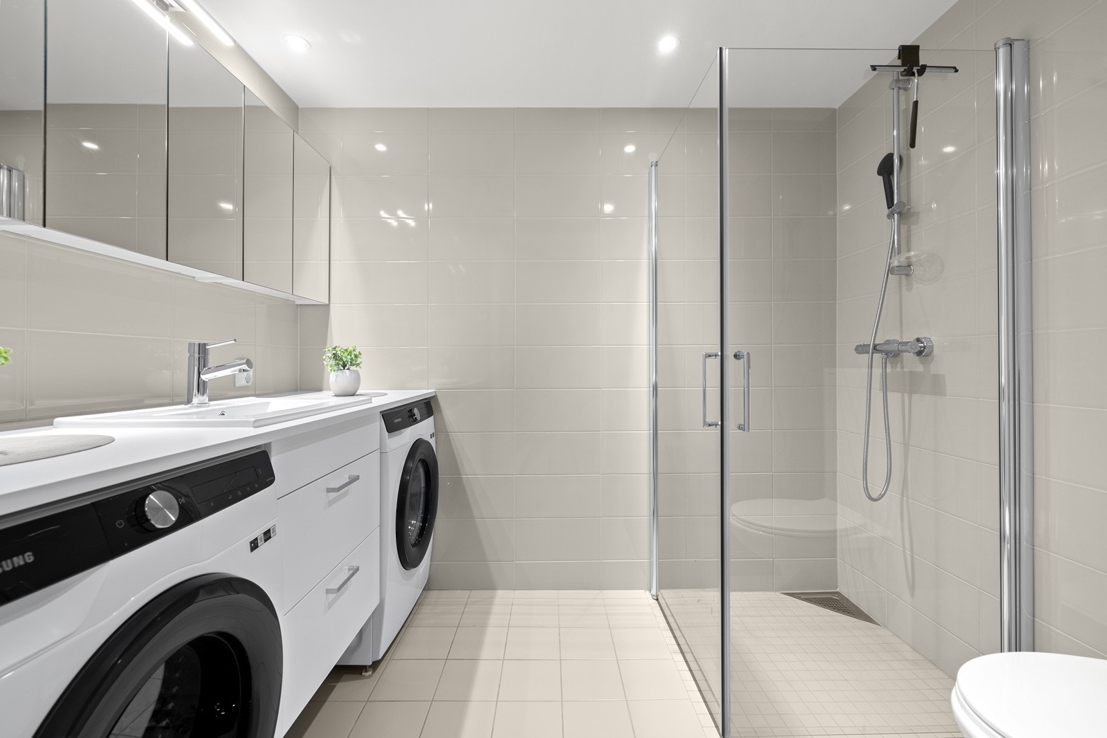 Delikat og lekkert hovedbad med opplegg for vaskemaskin og tørketrommel. Galleribilde