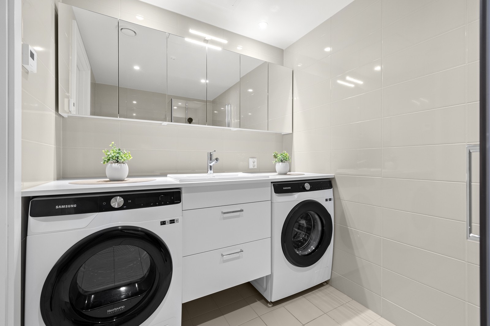 Badet er utstyrt med vegghengt toalett, servant med skuffer og dusjnisje med innfellbare glassdøre Galleribilde