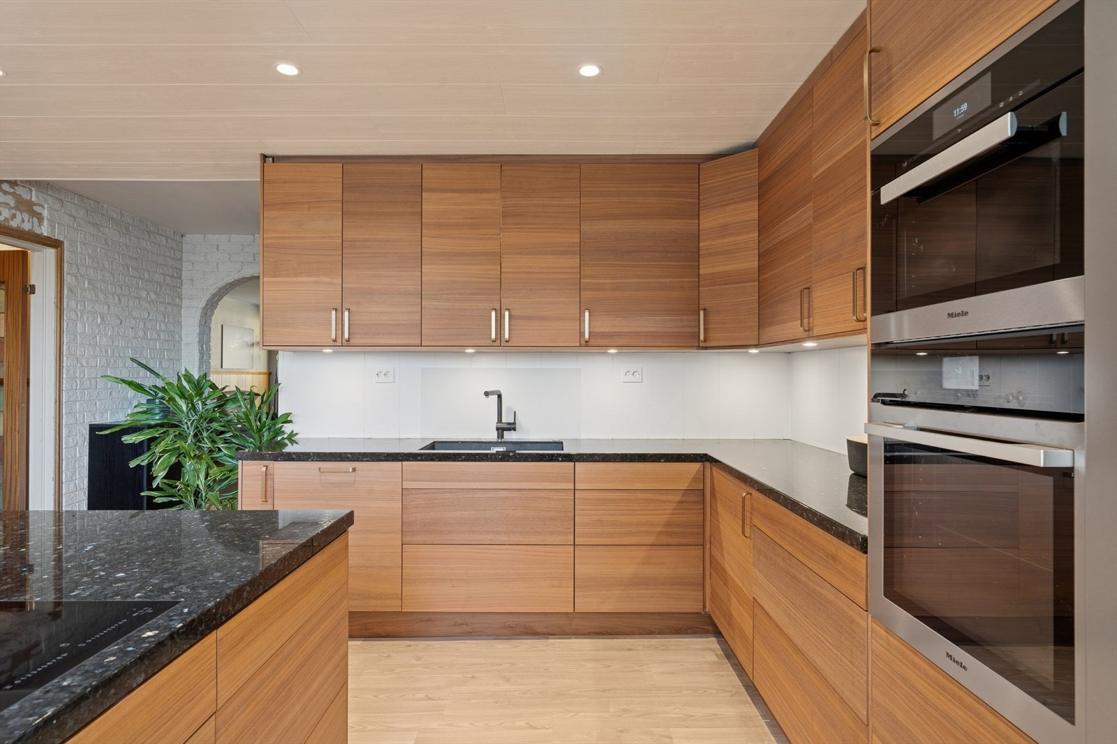 Moderne kjøkken fra 2020 med slette fronter og benkeplate i granitt med underlimt kum og ettgreps blandebatteri. Galleribilde