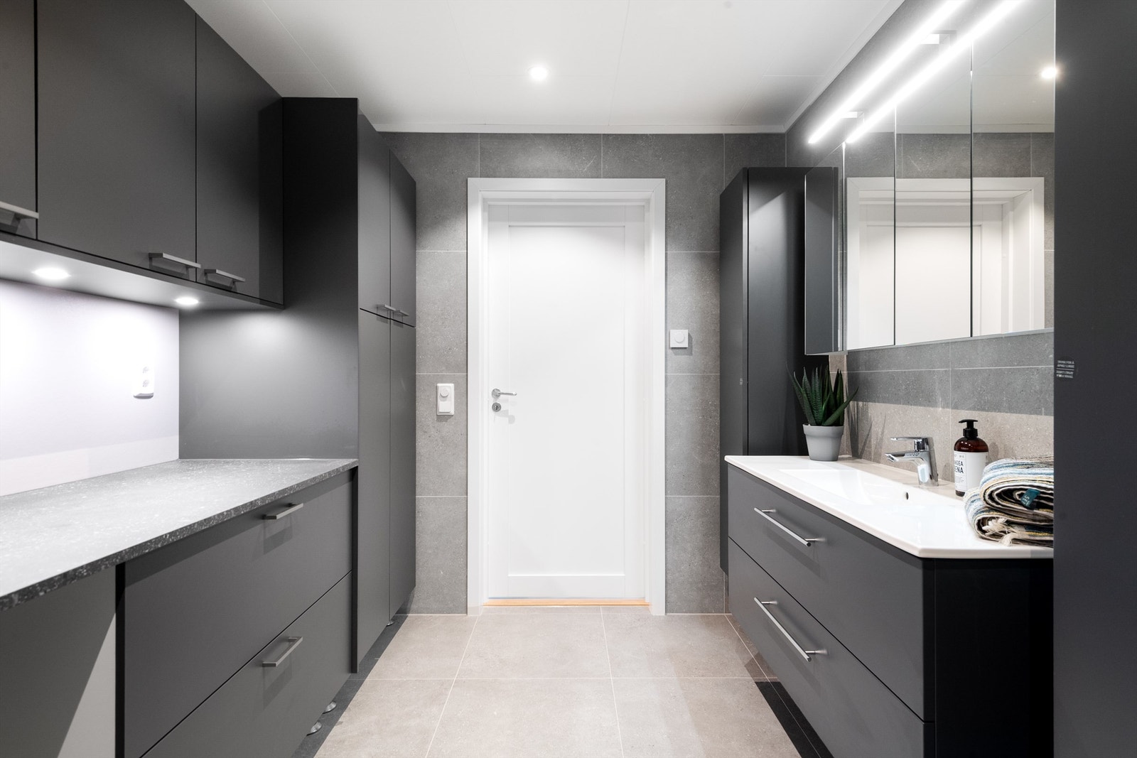 Praktisk og innholdsrikt våtrom med opplegg for vaskemaskin, vegghengt toalett og dusjhjørne med glassdører Galleribilde