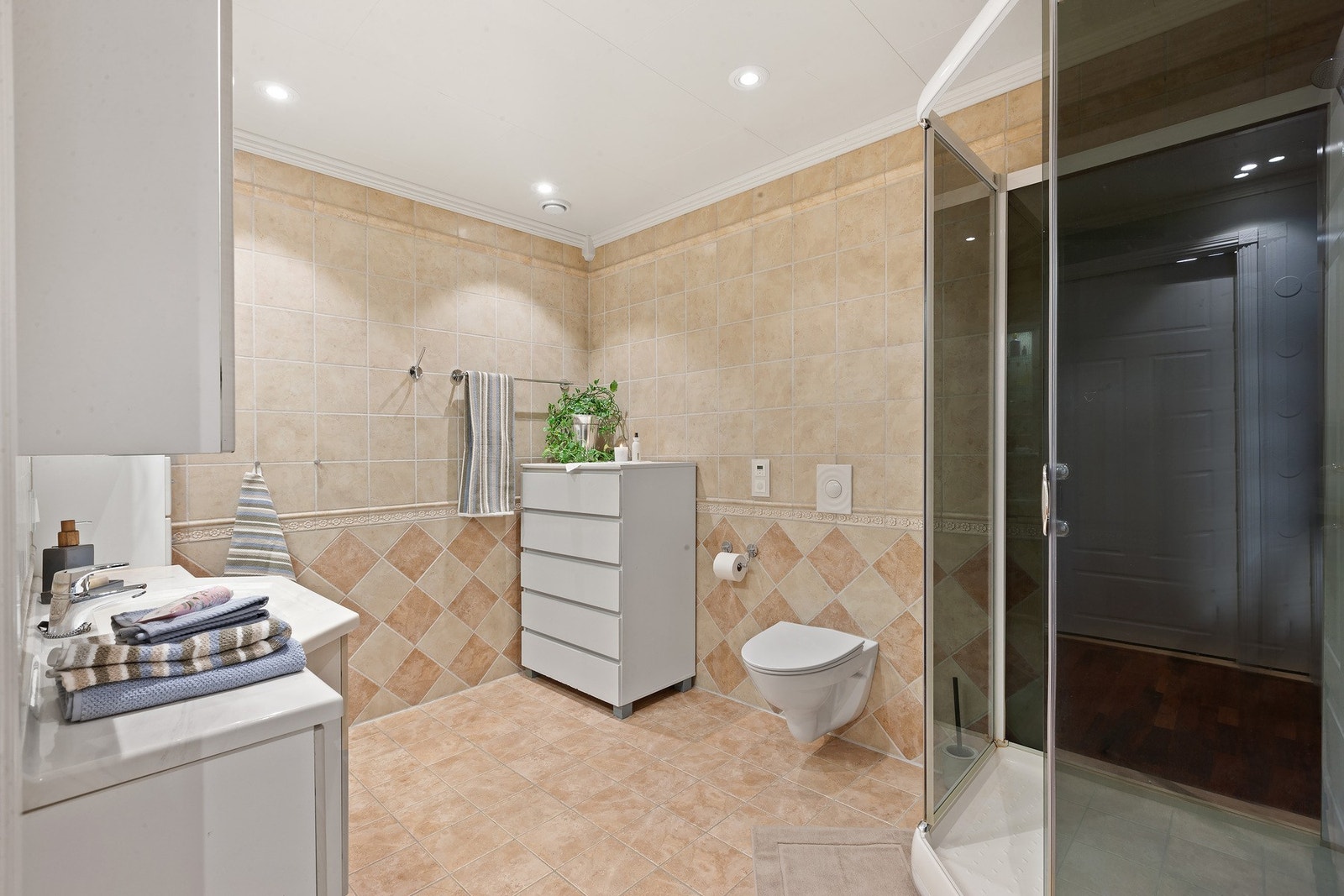 Badet i hovedetasjen med helfliset utførelse med gulvvarme, innredning, dusjkabinett og toalett. Galleribilde