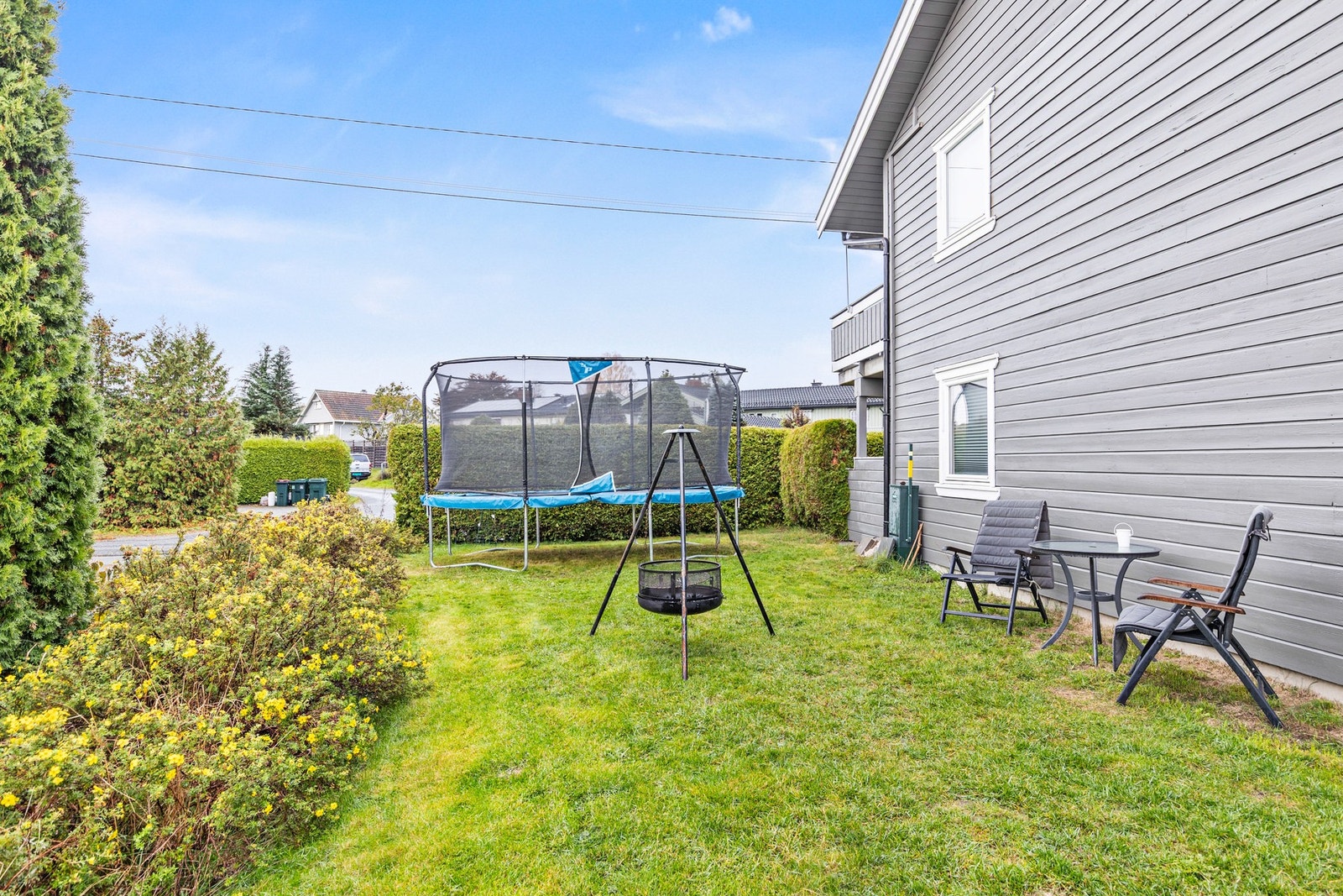 Koselig felleshage i sameiet som er opparbeidet med bålplass, sittegruppe og trampoline. Galleribilde