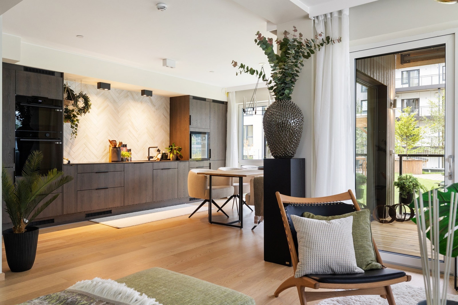 Kjøkken har innredning med glatte fronter og benkeplate av stein Galleribilde