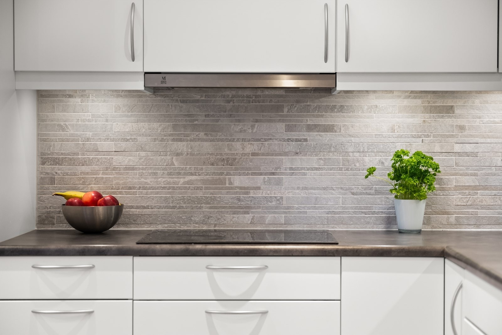 Kjøkkenet har flislagt gulv, og veggen over kjøkkenbenken er også flislagt for en praktisk og stilren løsning. Galleribilde