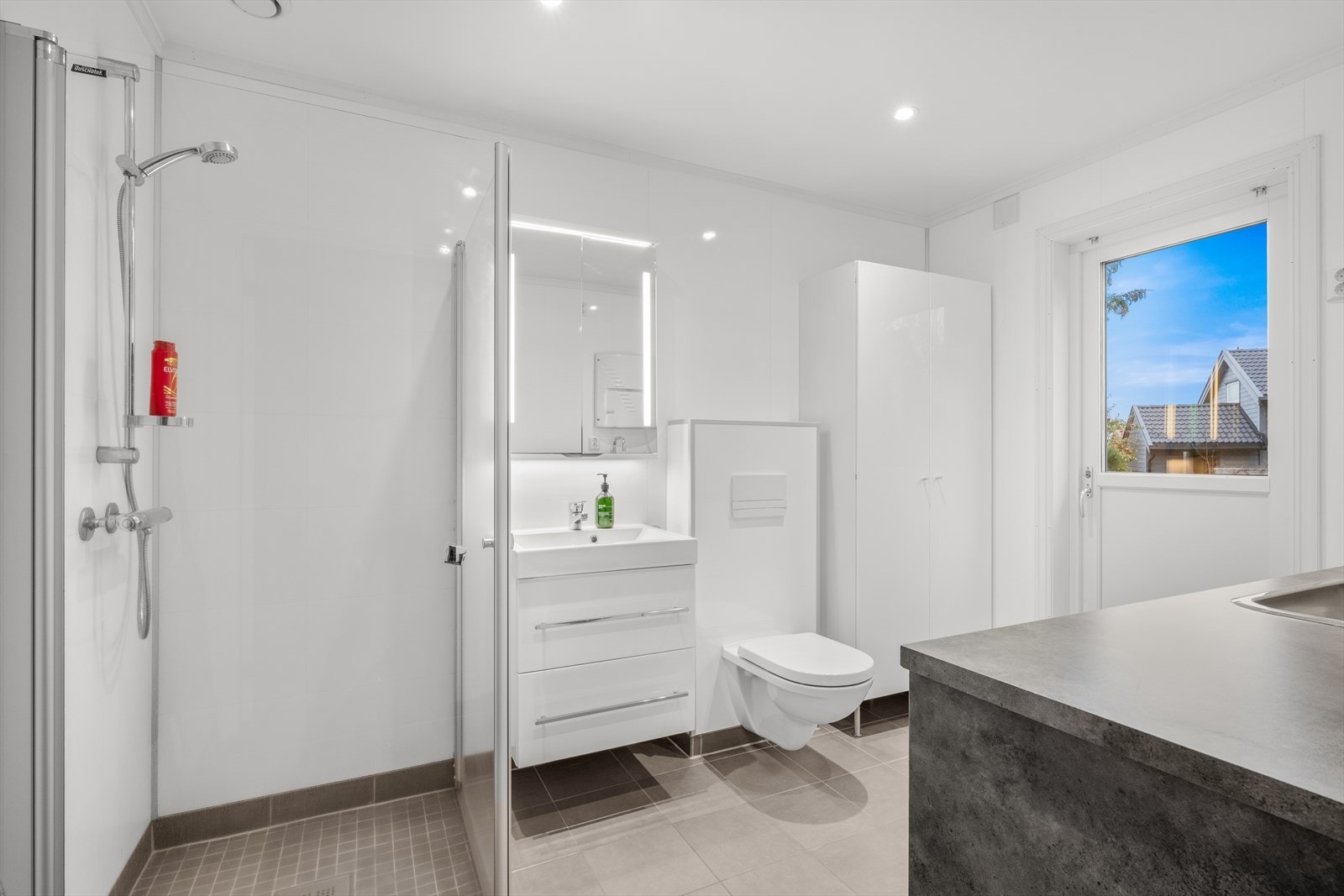 Bad/vaskerom er utstyrt med vegghengt toalett, dusj og baderomsinnredning med LED-speil. Galleribilde