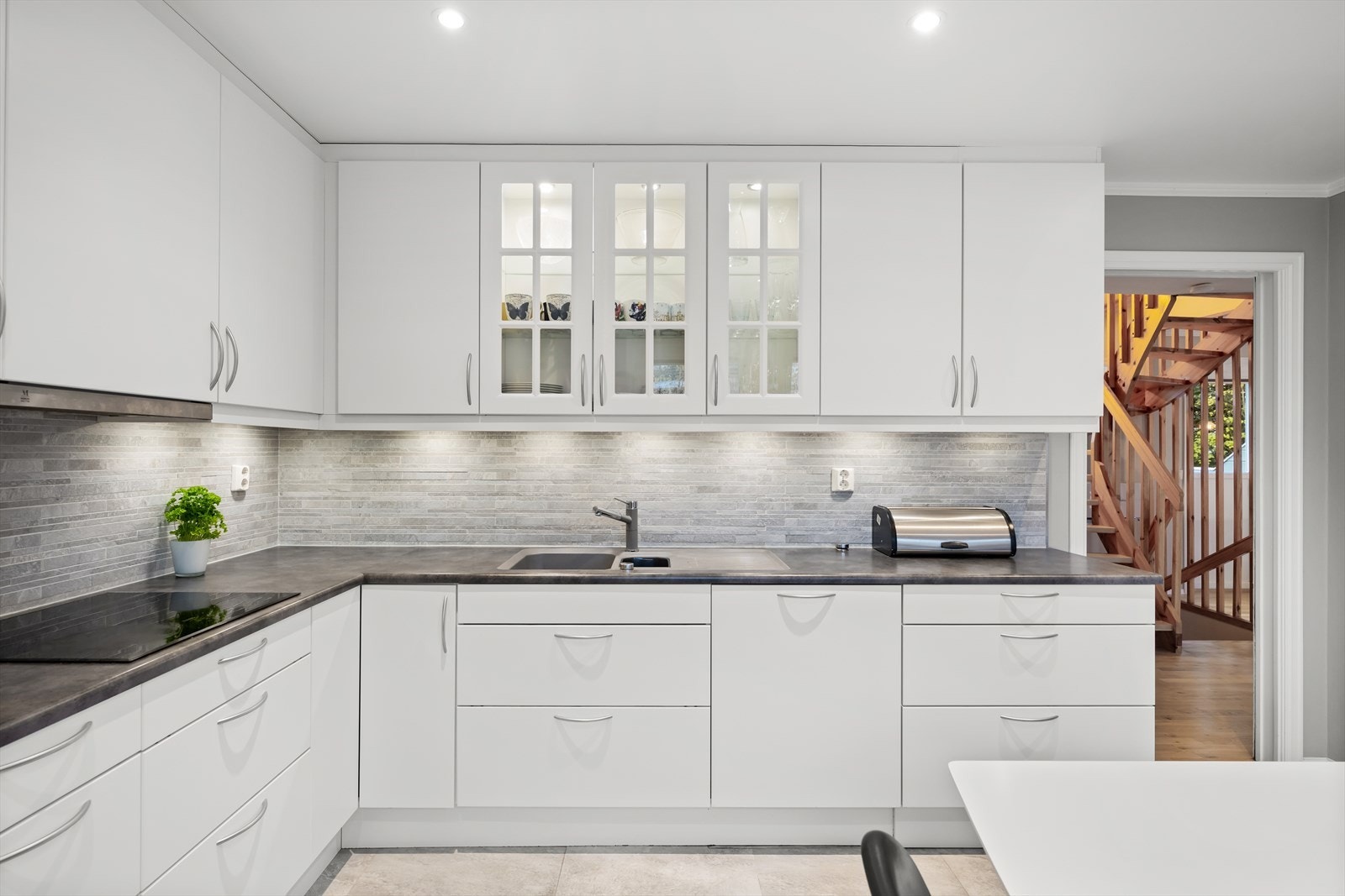 Pent kjøkken med lyse, glatte fronter og laminat benkeplate. Galleribilde