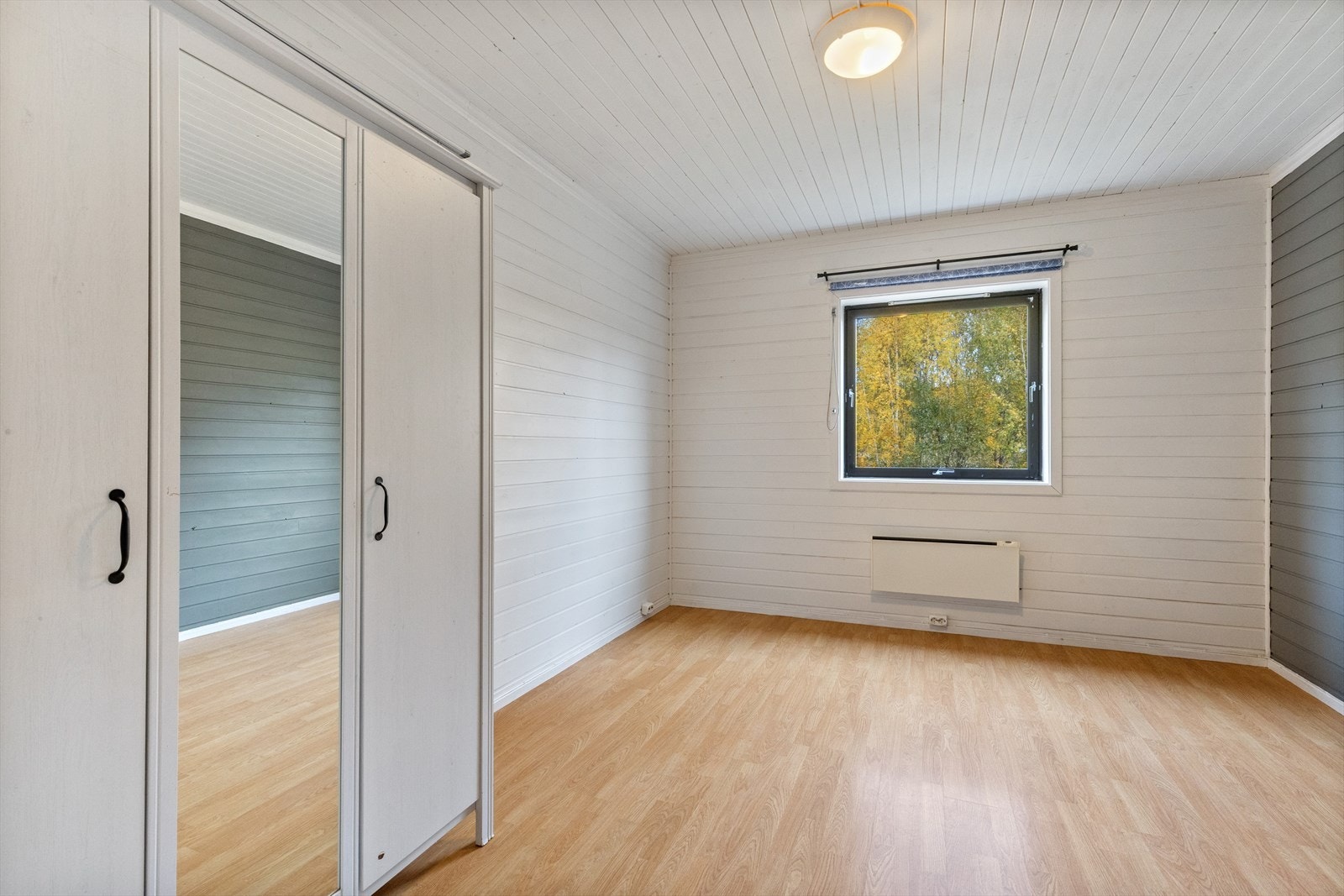 Soverom 2 med kontrastamlt vegg, har garderobeskap, østvendt vindu med rullegardin og panelovn montert på vegg. Galleribilde