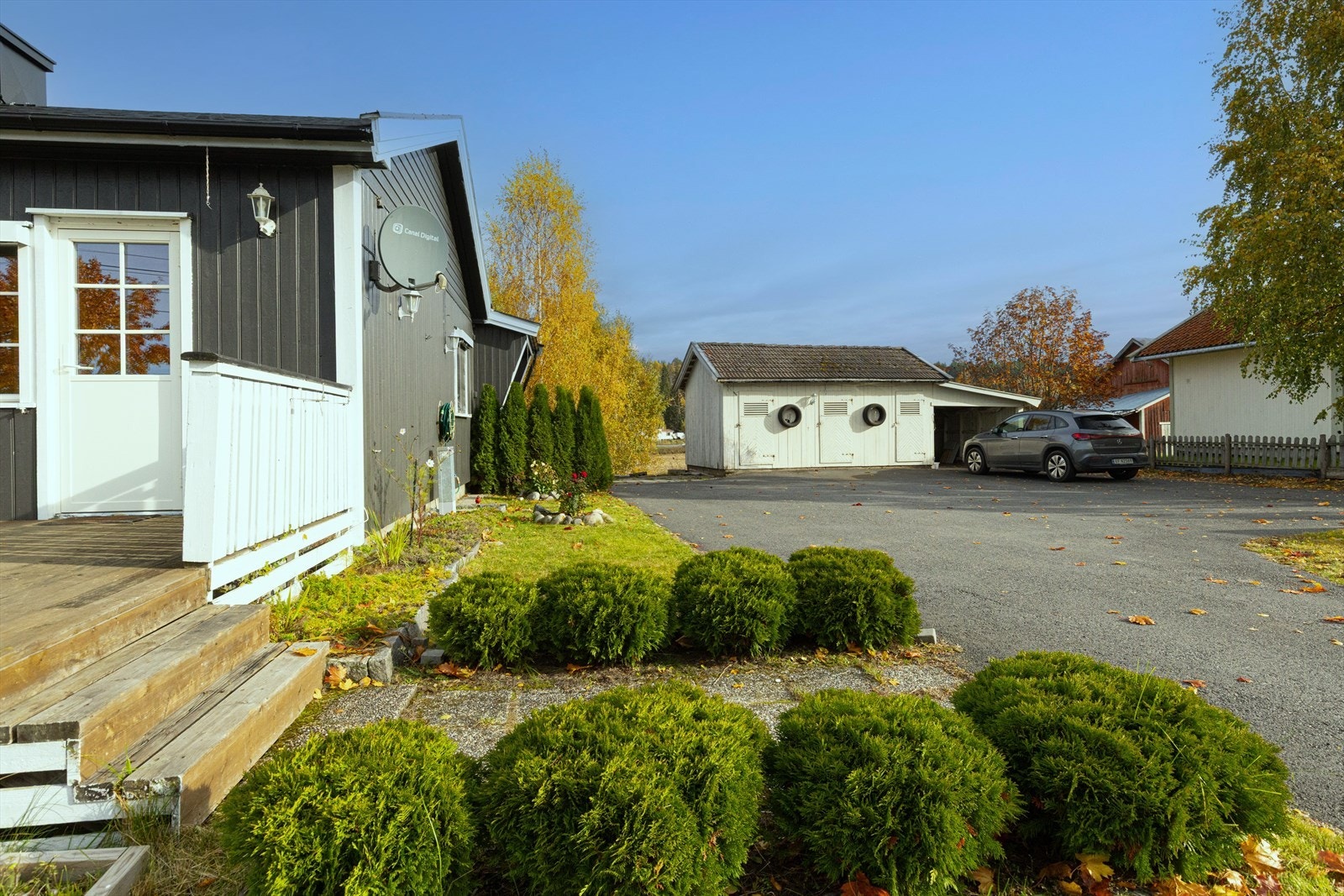 Innkjøring og gårdsplass, asfaltert i 2020, har uthus med 2 boder og carport med strøm. Galleribilde