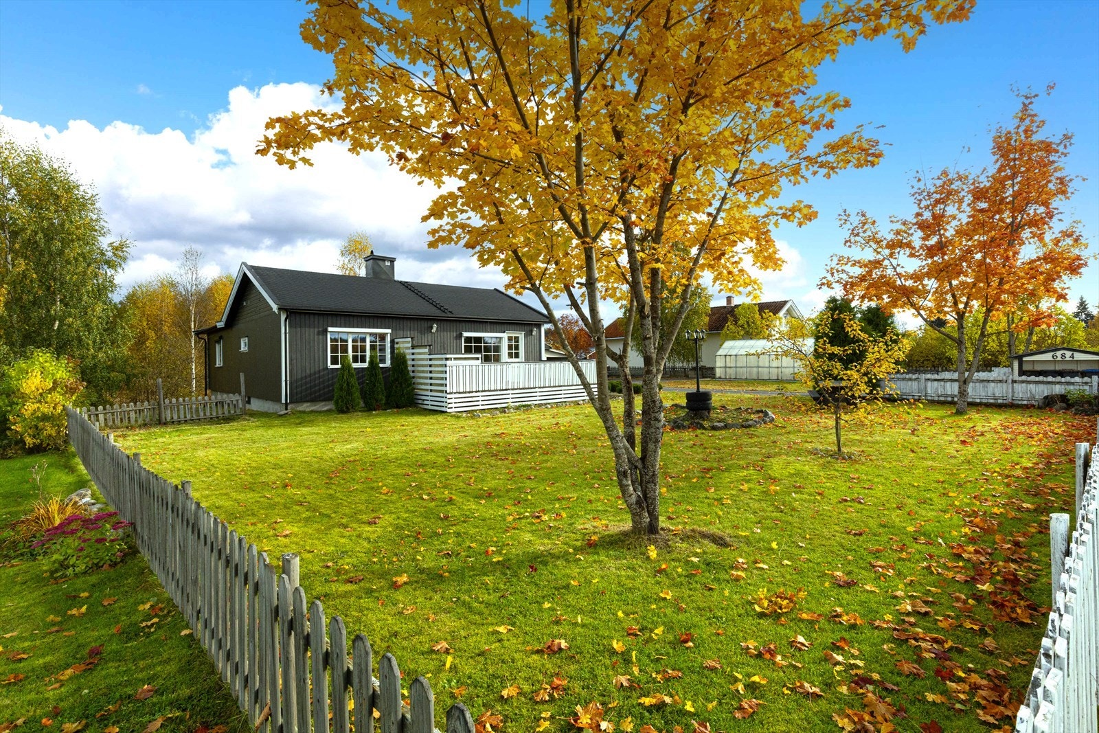 Eiendommen har pent beplantet hage med plen, busker og trær. Galleribilde