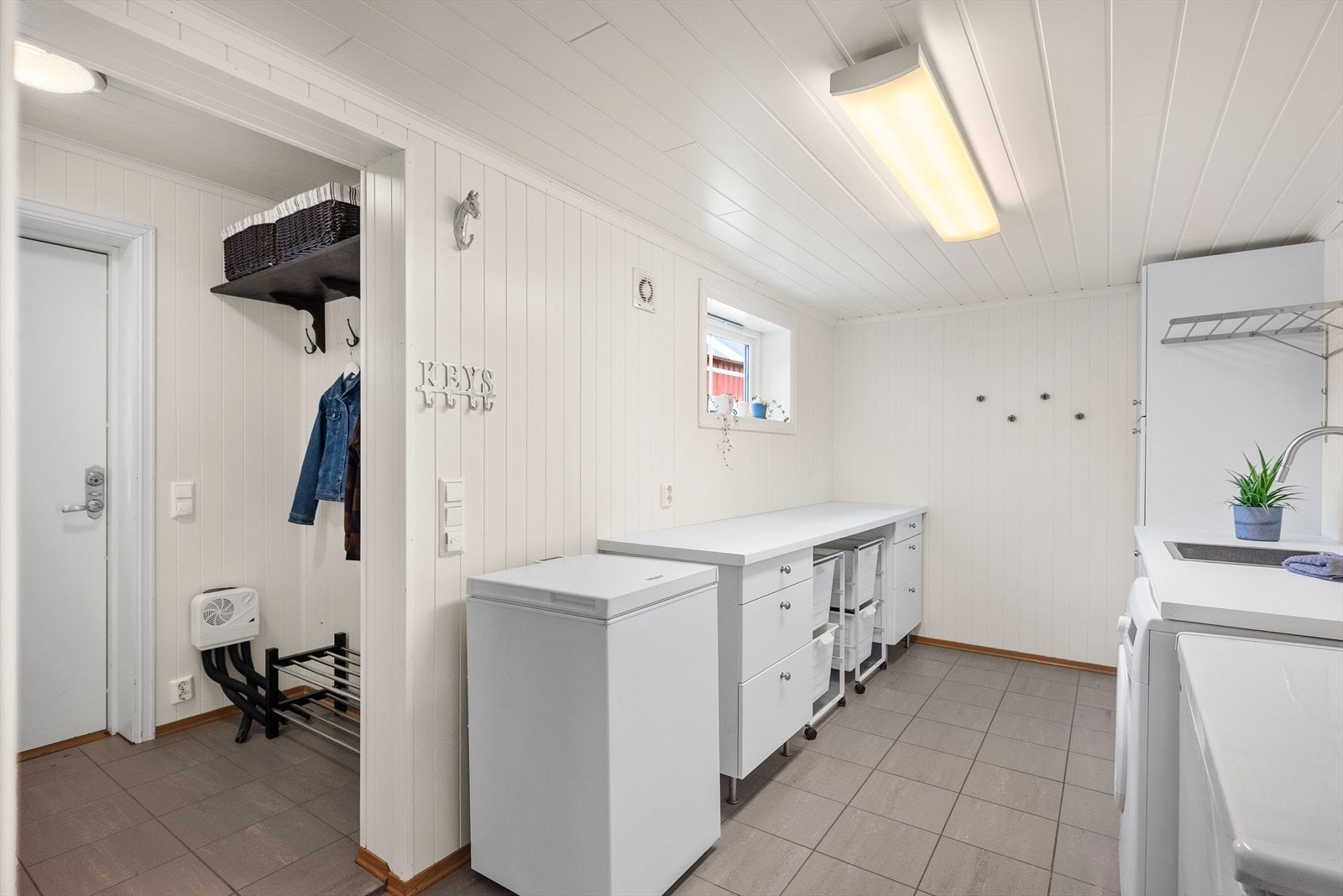 Ved inngangsparti finner vi et meget praktisk vaskerom med flis på gulv og panelplater på vegger. Malt panel i himling. Gulvvarme. Utstyrt med opplegg for vaskemaskin, servantskap og mekanisk avtrekk Galleribilde