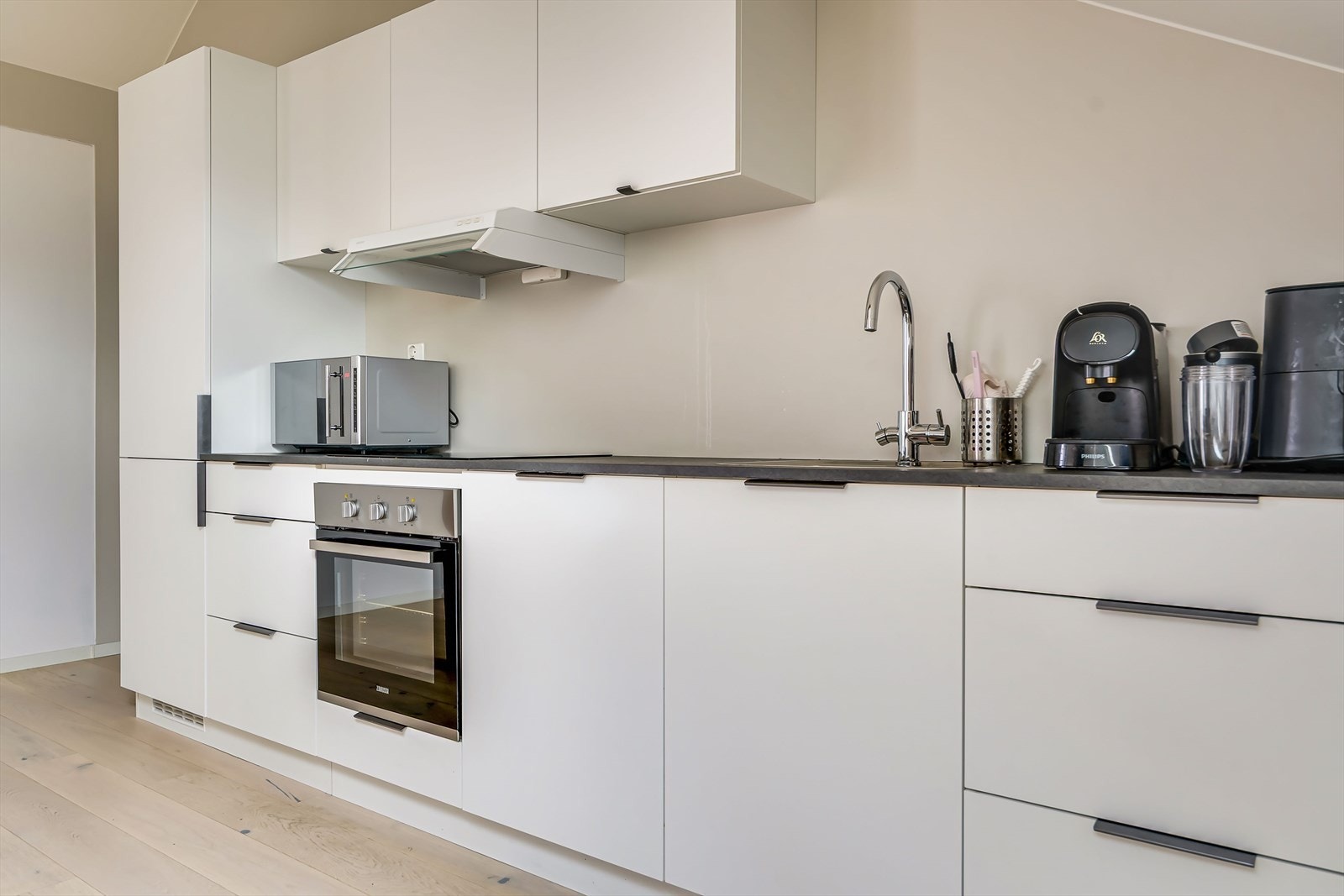 Innredning med glatte, folierte fronter og laminat benkeplate med nedfelt kum i rustfritt stål - Vaskemaskin, oppvaskmaskin, to stk store kjøleskap, en stk fryser og mikro medfølger Galleribilde