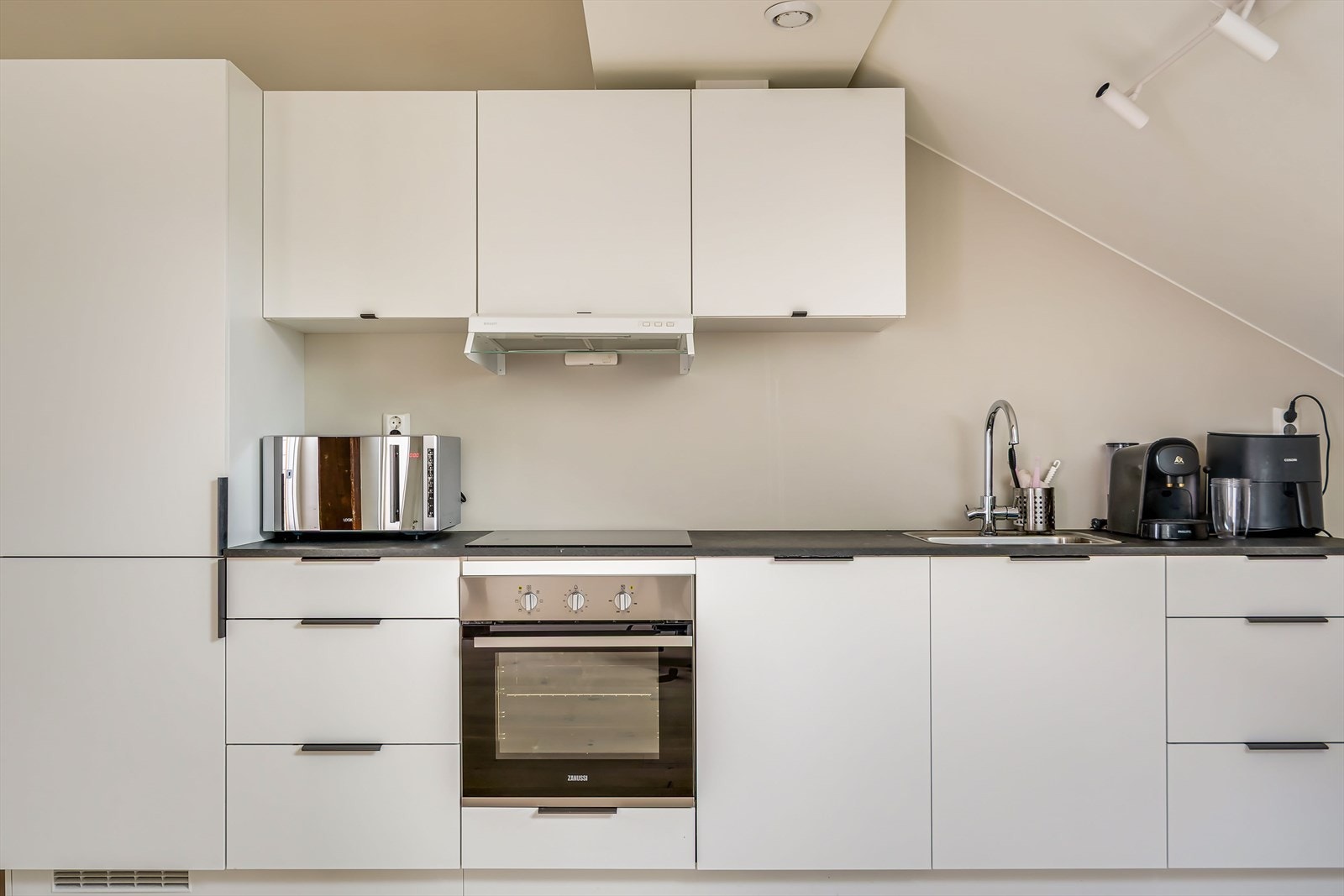 Integrert induksjonsplatetopp, stekeovn, oppvaskmaskin, kjøle-/fryseskap, samt fullhøyde kjøleskap Galleribilde