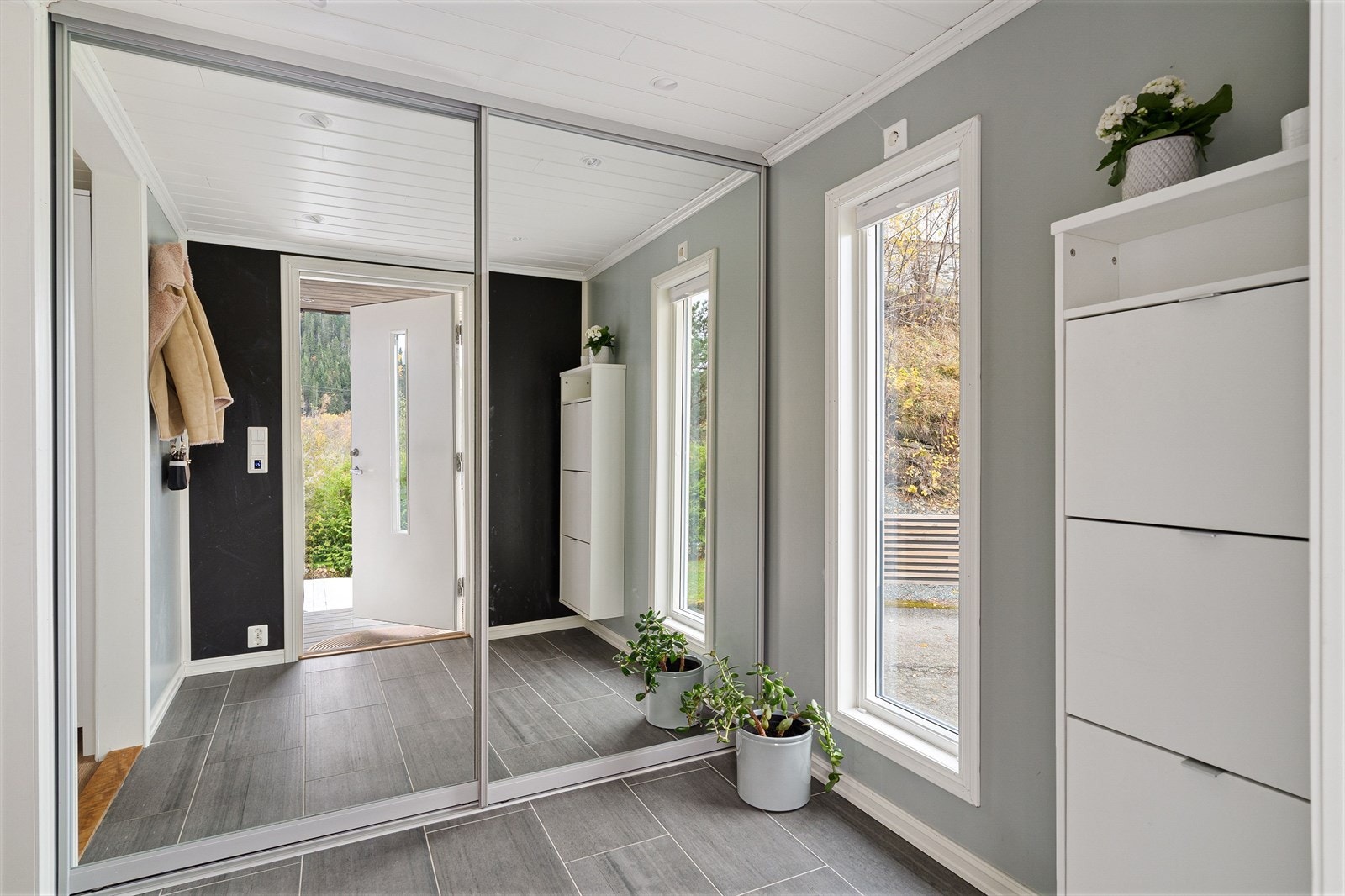 Det overbygde inngangspartiet leder til innbydende entré med bred skyvedørsgarderobe. Galleribilde