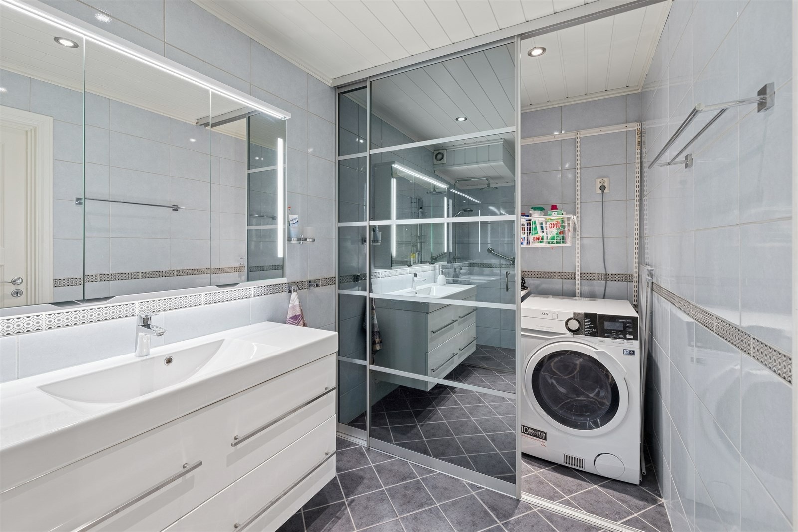 Flislagt baderom fra 2013 med elektriske varmekabler i gulv og panel i taket. Badet er utstyrt med innredning med nedfelt servant, dusjvegger/hjørne og opplegg for vaskemaskin. Varmtvannsbereder står også i dette rommet. Galleribilde