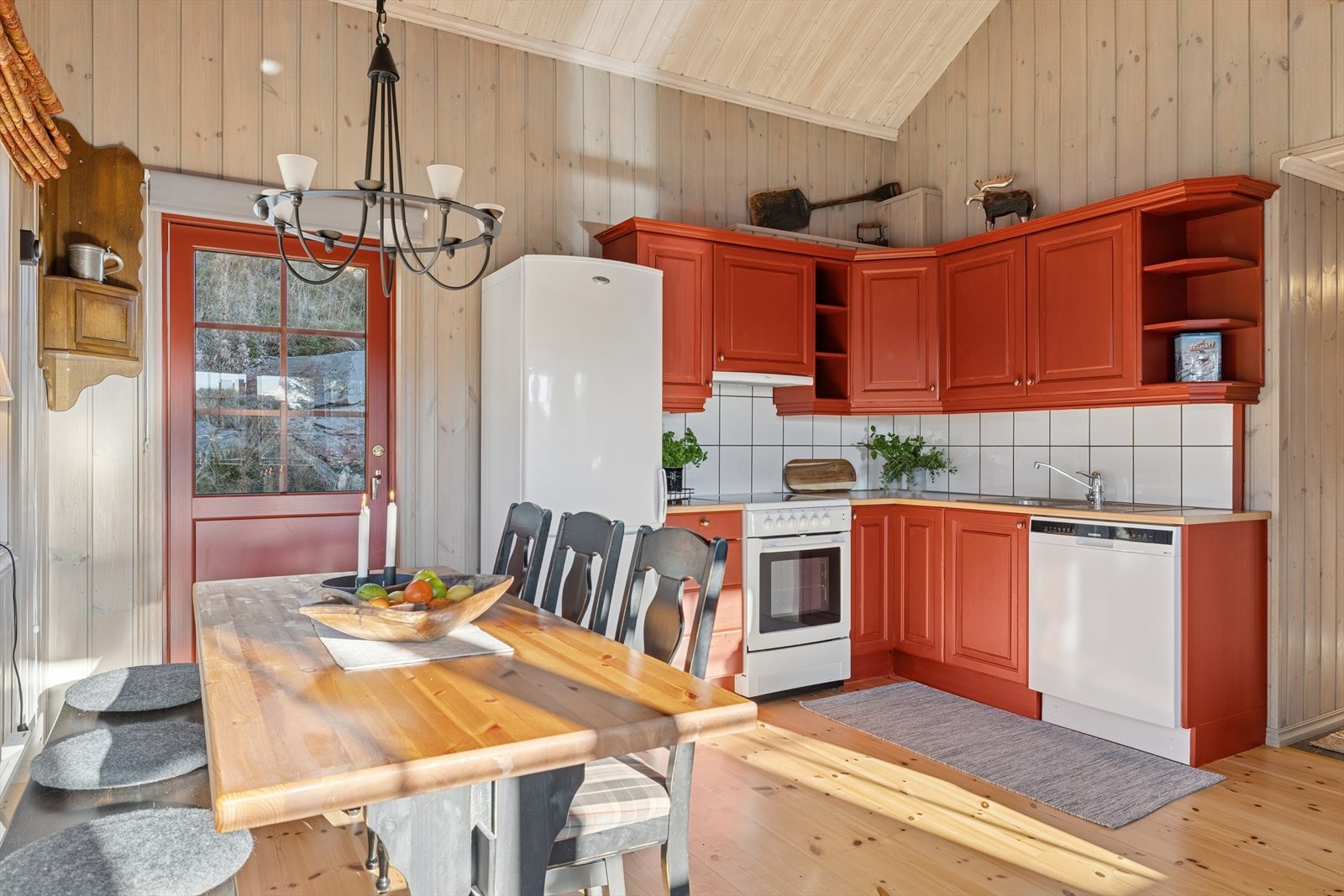 L-formet kjøkken, praktisk plassert i den åpne løsningen mot stuen - med god skapplass og stilren Rørosrød-innredning. Galleribilde