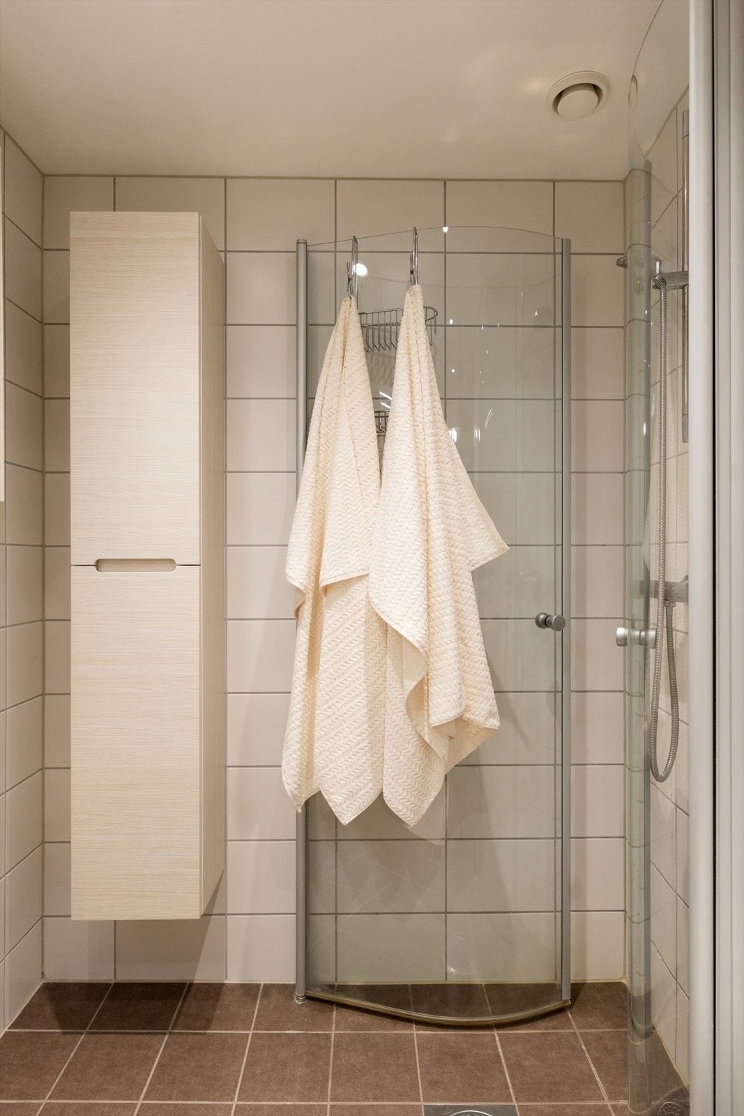 Badet er innredet med vegghengt klosett, servant nedfelt i innredning, speilskap m/lys og dusjhjørne med svingbare glassdører. Galleribilde
