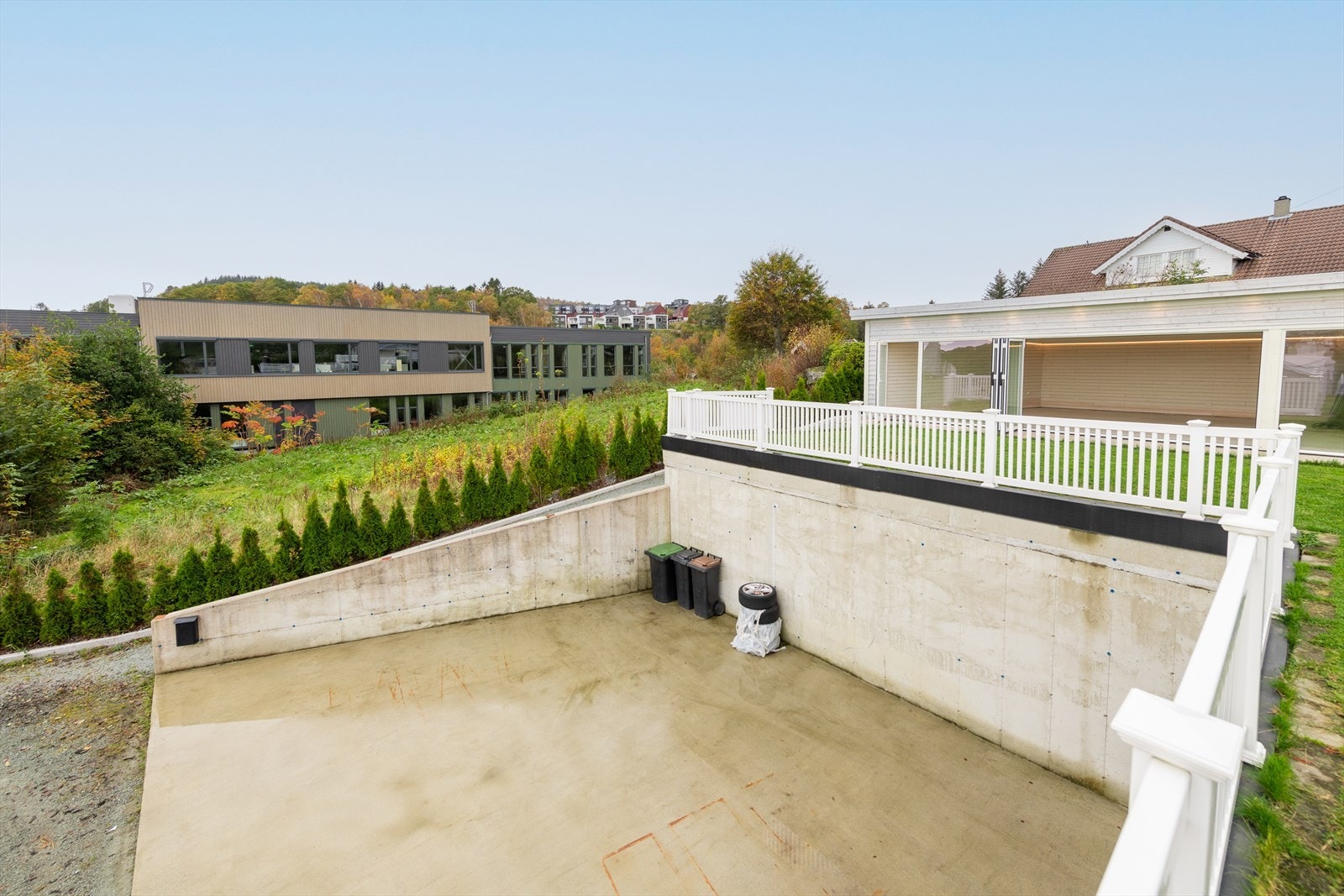 Romslig parkeringsområde med tre solide stålbjelker på hver side, tilrettelagt for enkel etablering av carport ved behov. Galleribilde