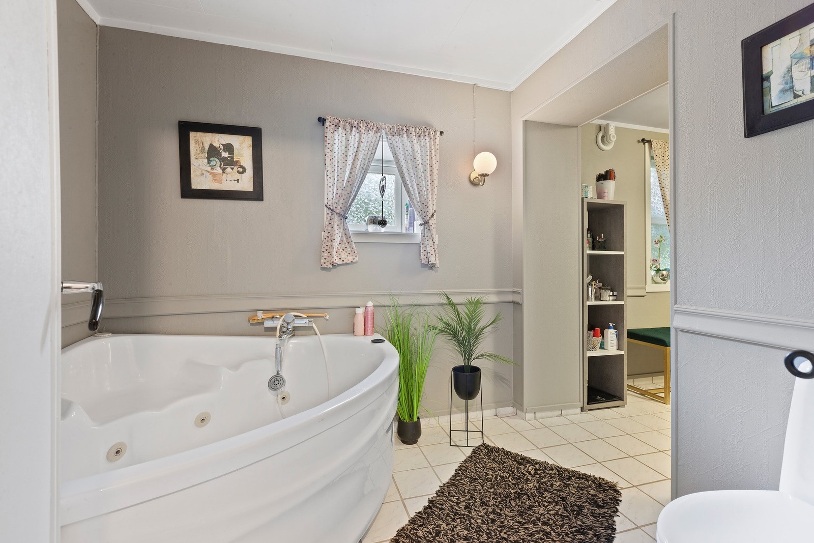 Romslig bad delt inn i to soner med hjørnebadekar og dusj. Galleribilde