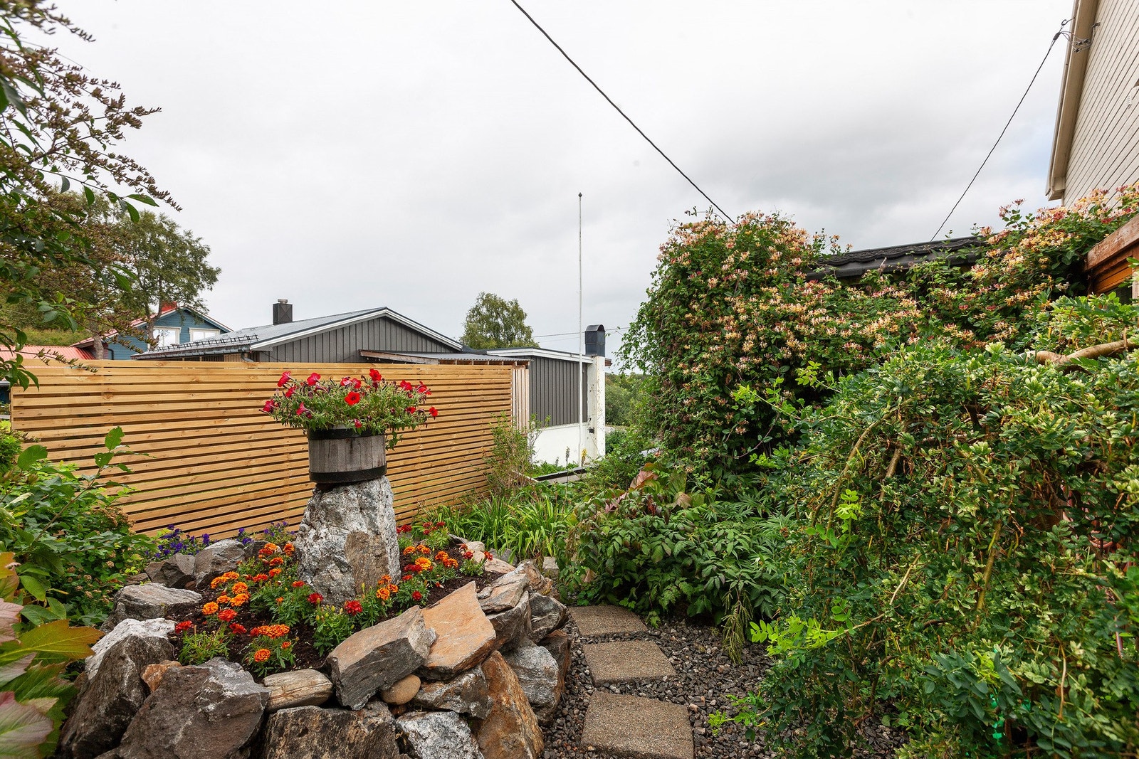 Pent opparbeidet hage med beplantning og hellelagte områder og passasjer. Galleribilde