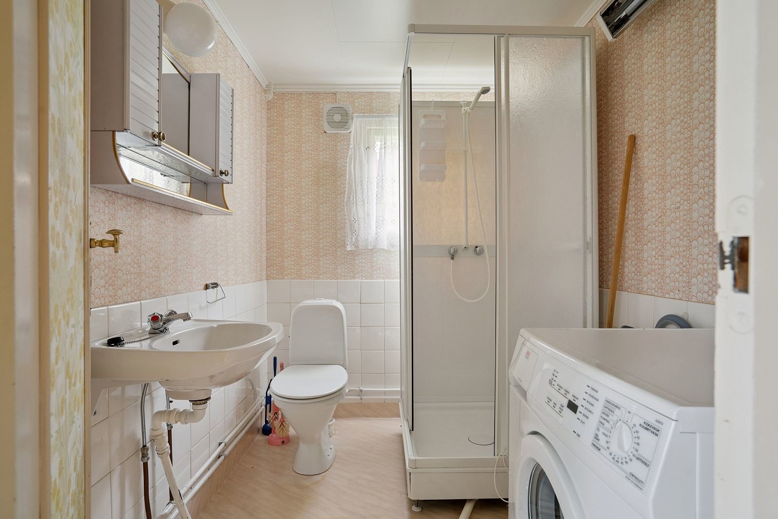 Lyst bad med vaskemaskin og dusjhjørne.