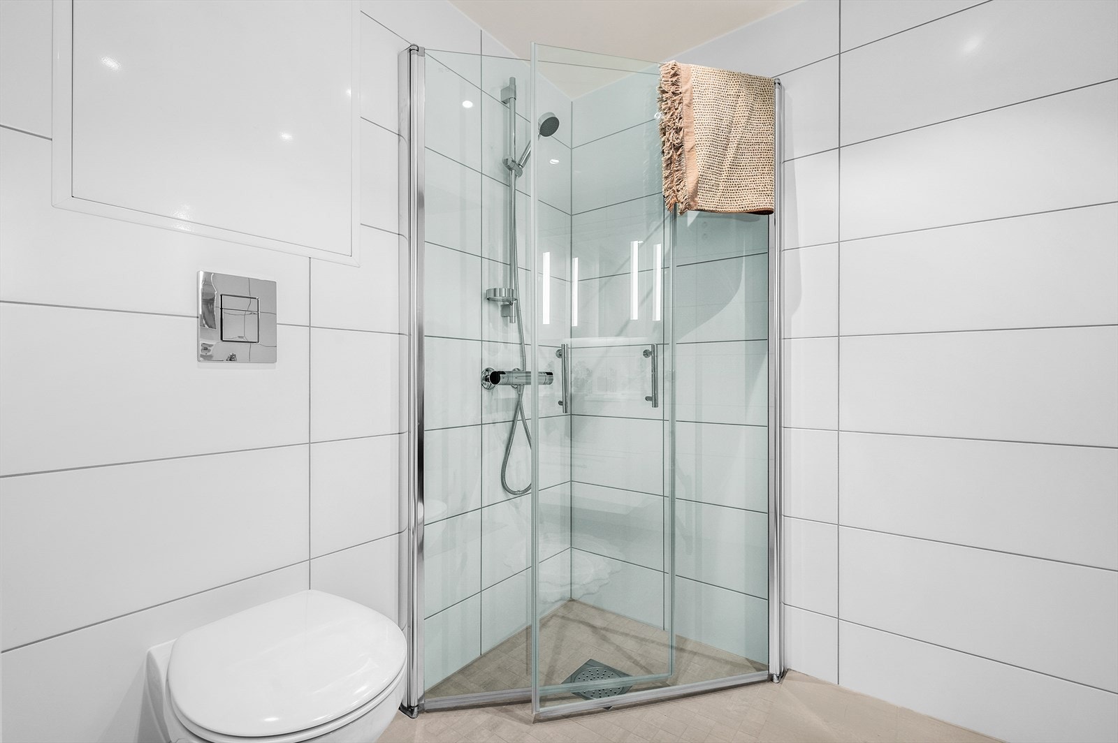 Badet byr på veggmontert innredet servant og toalett, opplegg for vaskemaskin samt praktiske innfellbare dusjdører. Det medfølger leiligheten Galleribilde