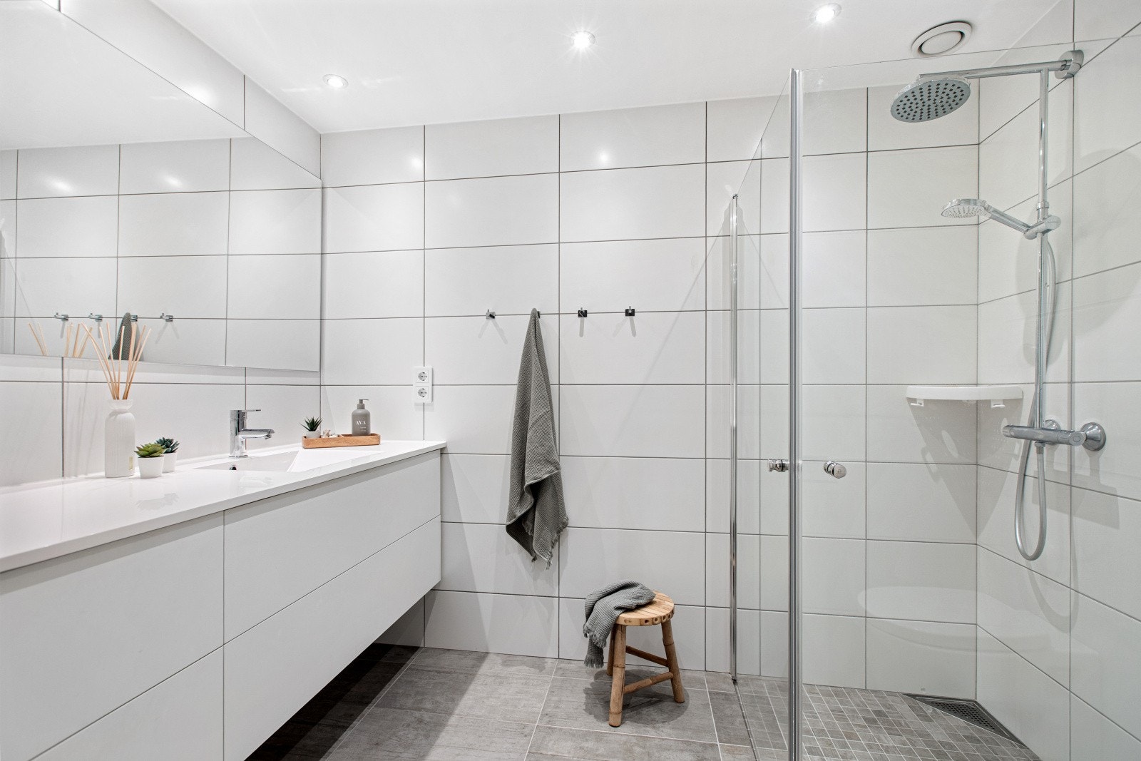 Badet er i tidløse farger og består av veggmontert klosett, dusjhjørne og romslig servantinnredning Galleribilde