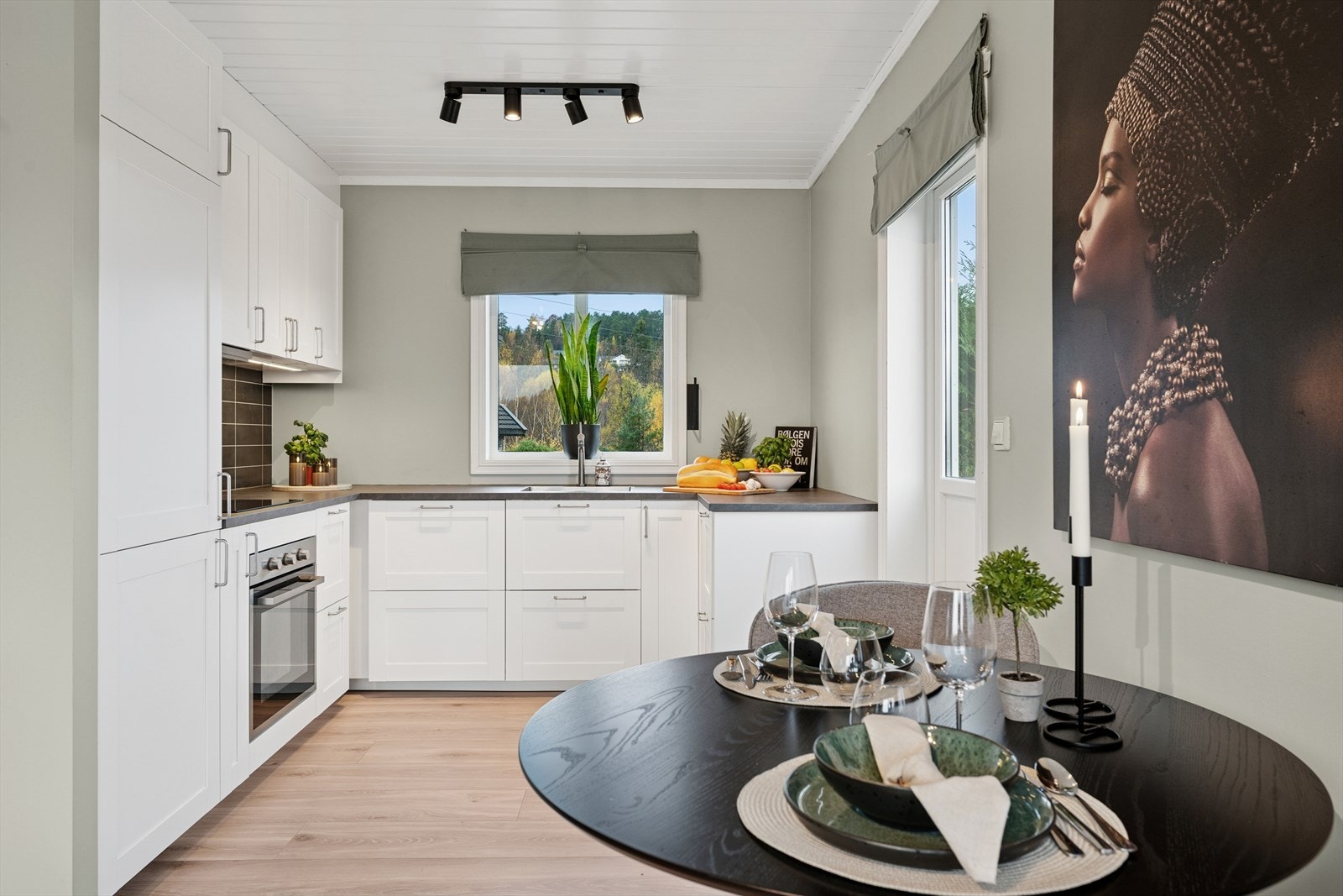 Kjøkkeninnredningen har profilerte fronter og laminat benkeplate med nedfelt kum i rustfritt stål. Galleribilde