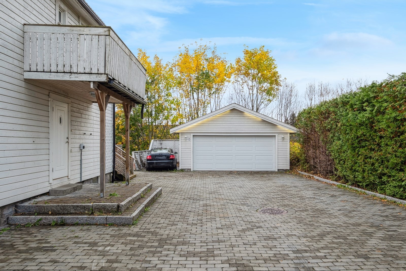 Brosteinsbelagt gårdsplass og stor garasje Galleribilde
