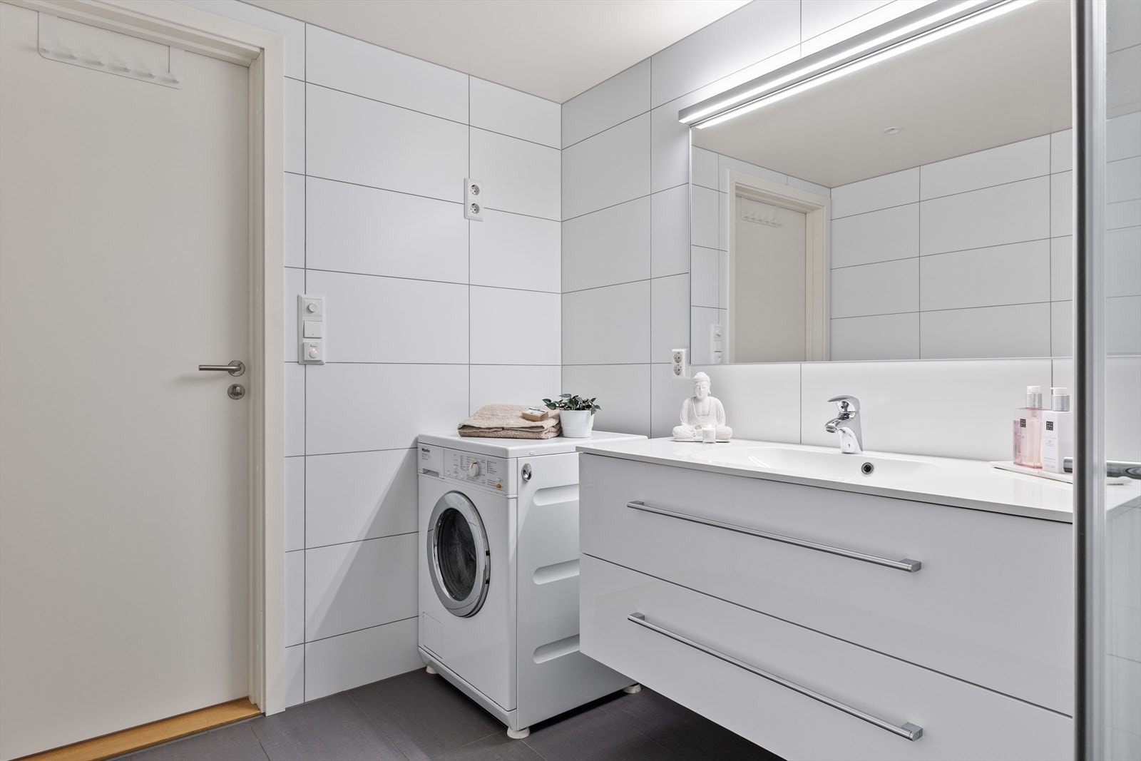 Her er det flislagt gulv med elektriske varmekabler som gir en behagelig varme under føttene, og flislagte vegger som gir et rent og elegant uttrykk. I taket er det malte plater med stilfulle downlights, som sørger for jevn og behagelig belysning. Galleribilde