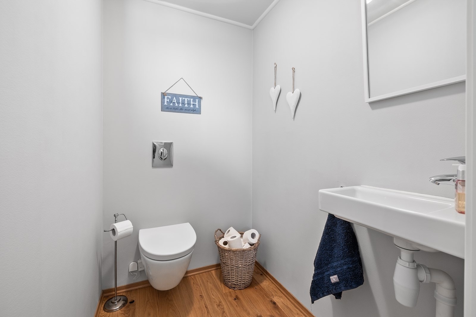 Toalettrom med 1-stavs parkett på gulv og malte plater på vegger og tak. Rommet er innredet med servant, speil og vegghengt klosett. Galleribilde