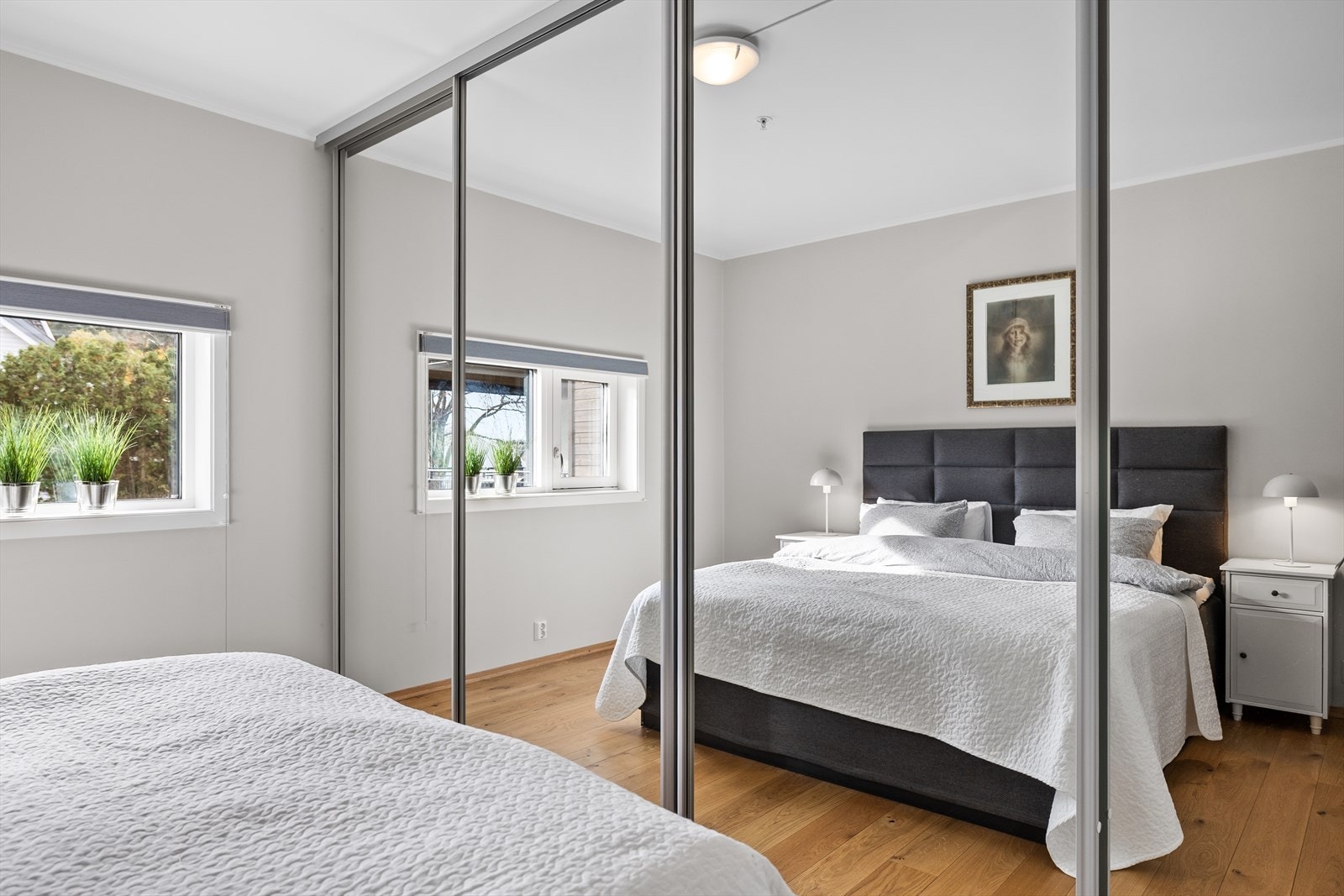 En romslig skyvedørsgarderobe gir rikelig med oppbevaringsplass og bidrar til et ryddig og stilrent uttrykk. Dette er et soverom som oser av komfort og harmoni - et perfekt sted å starte og avslutte dagen. Galleribilde