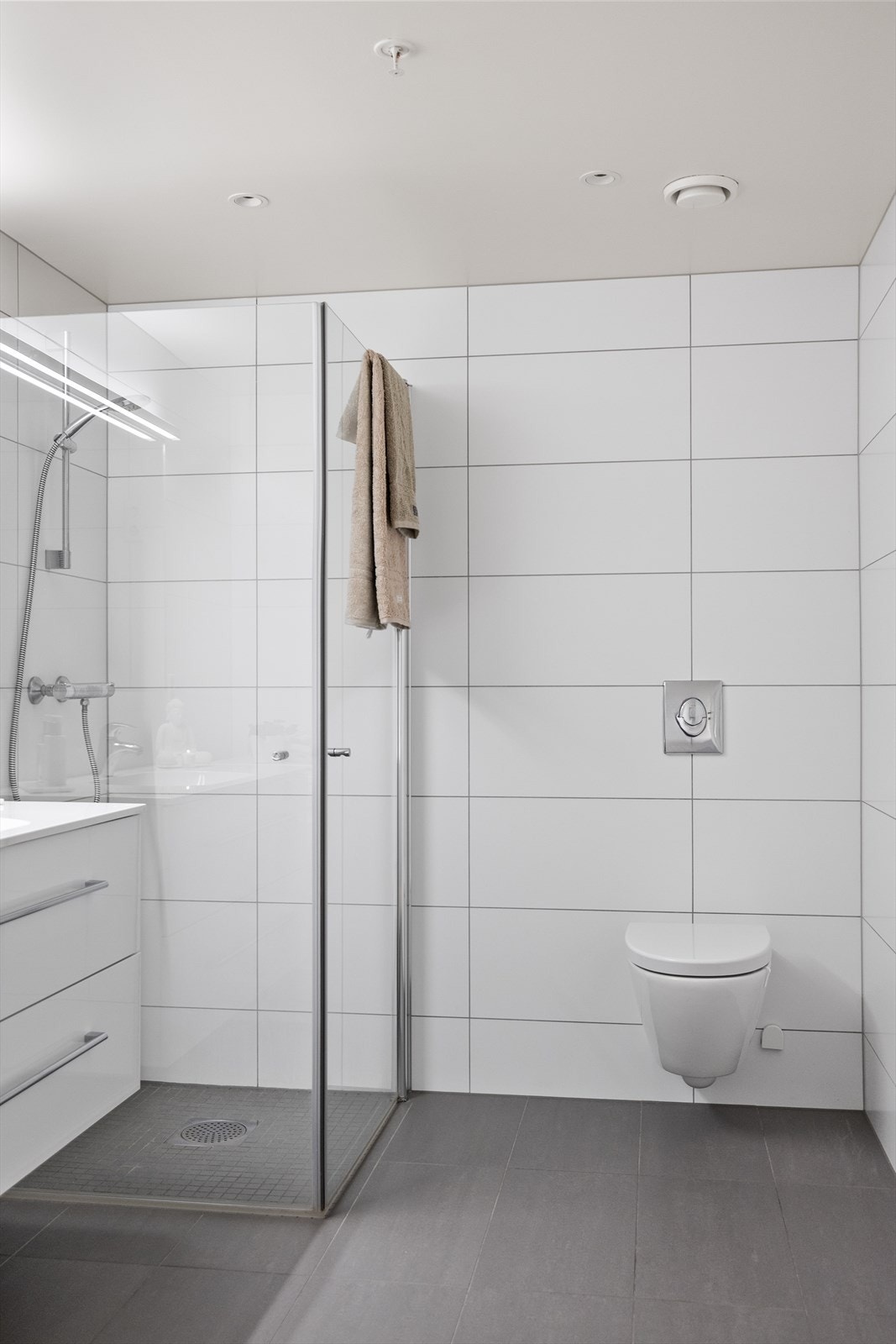 Rommet er innredet med dusjhjørne med glassvegger, servantskap med speil, og vegghengt klosett som gir et moderne og luftig preg Galleribilde