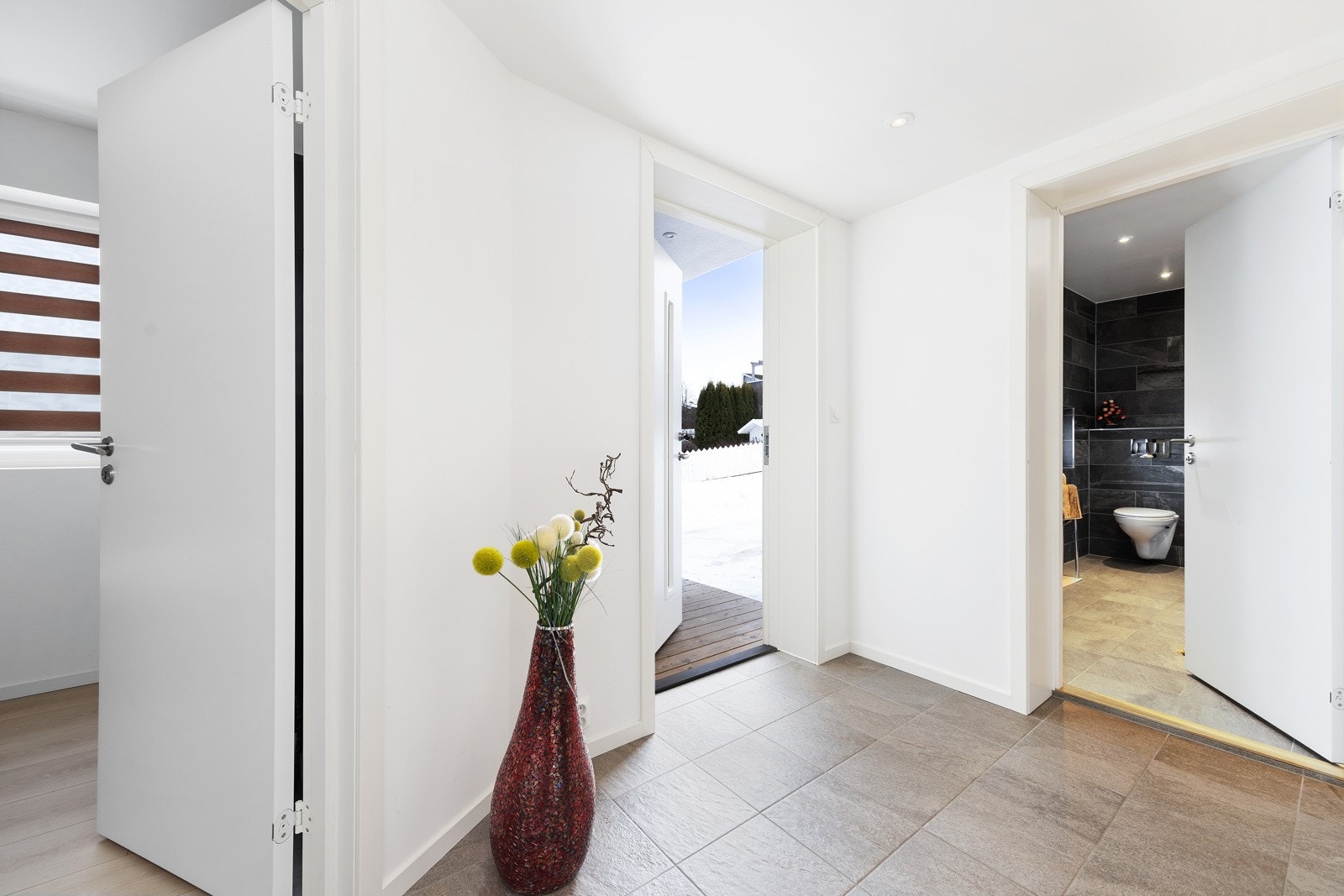 Gangen har varmekabler i gulvet og du har enkel tilgang til vaskerommet. Ved inngangsdøren har du tilgang til en utvendig bod i carporten. Videre inn i stuen finner du trappen som fører opp til 2. etasje. Galleribilde