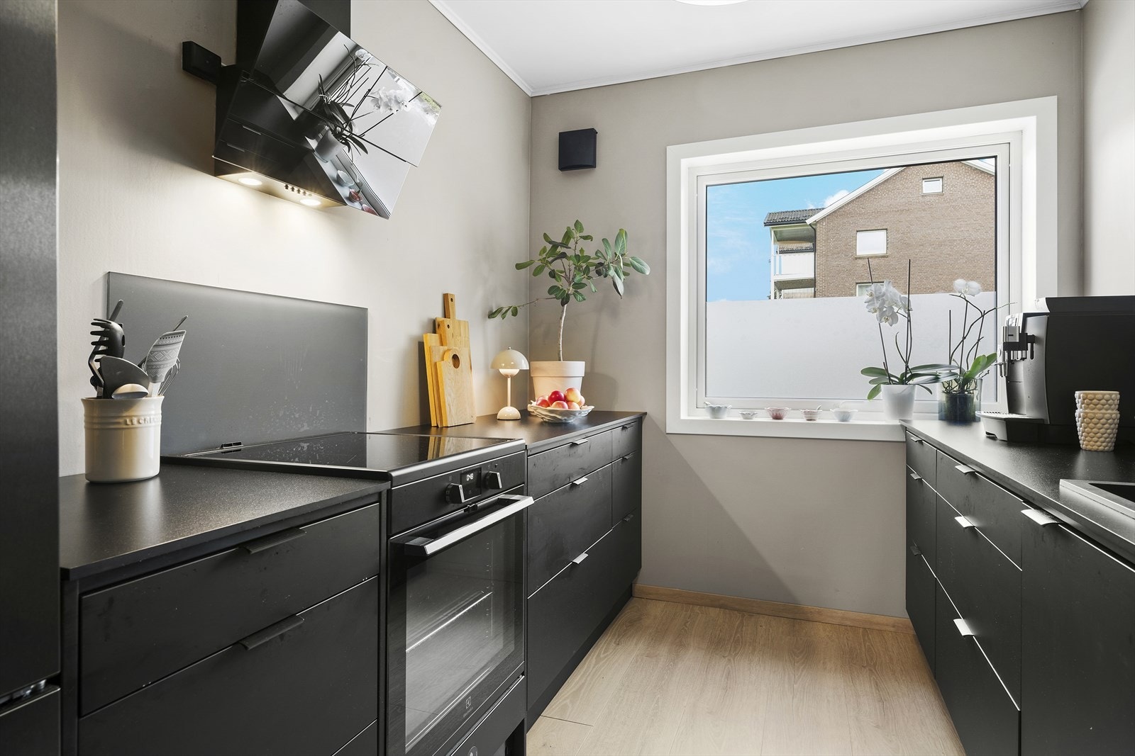 Kjøkkeninnredningen har sorte, slette fronter og laminert benkeplate Galleribilde