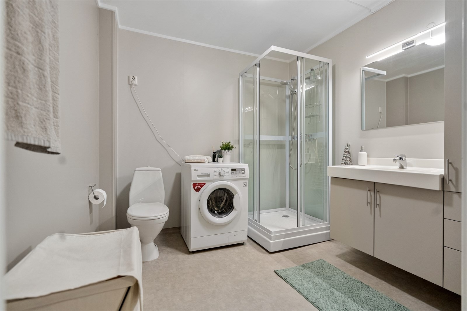 Badet er innredet med dusjkabinett, toalett, servant med oppbevaring og opplegg for vaskemaskin - alt du trenger i hverdagen Galleribilde