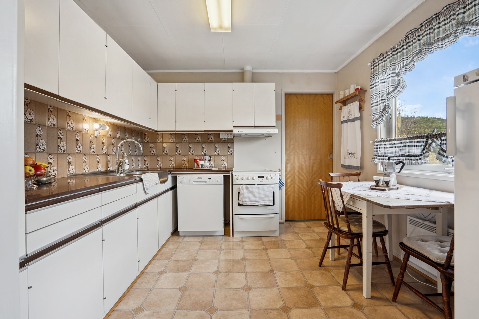 Kjøkkenet er utstyrt med frittstående hvitevarer som kjøleskap, oppvaskmaskin og stekeovn med koketopp. Galleribilde