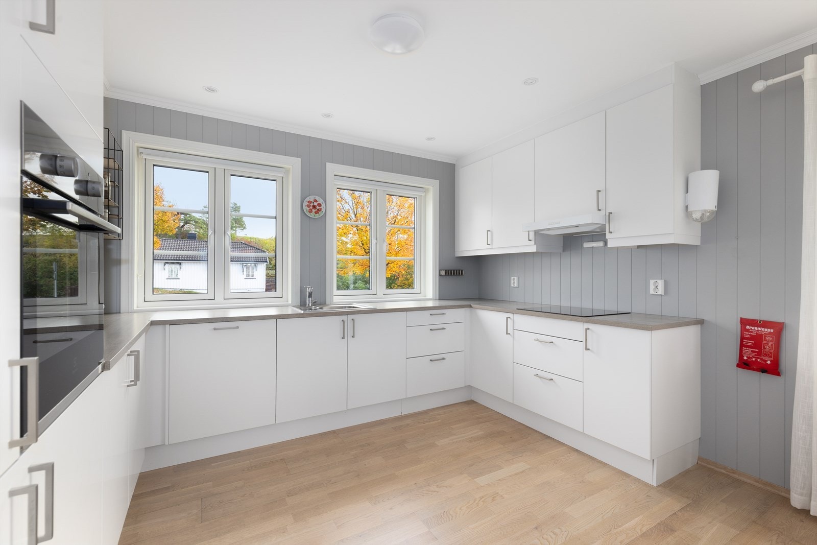 Innredningen har slette fronter og laminert benkeplate med nedfelt induksjonstopp. Det er integrert stekeovn, oppvaskmaskin og kjøl/fryseskap. Galleribilde