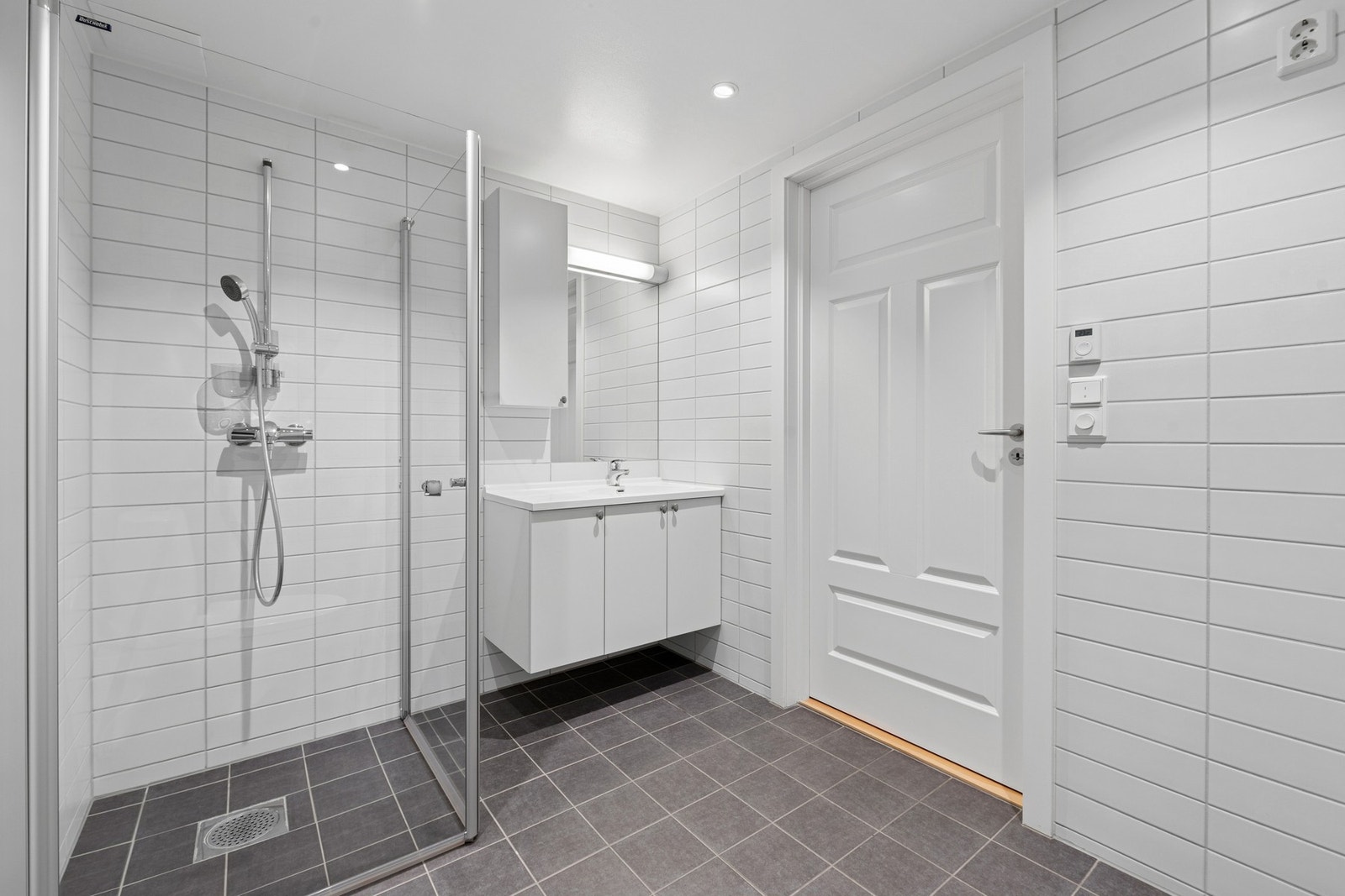 Badet er innredet med servant med underskap og speil med belysning, vegghengt skap for ekstra oppbevaring, dusjhjørne med glassvegger og frittstående toalett. Galleribilde