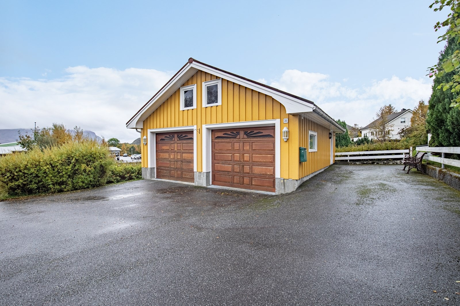 Dobbelgarasje med hems og asfalterte biloppstillingsplasser, det er også opparbeidet parkering på oppsiden av tomten Galleribilde
